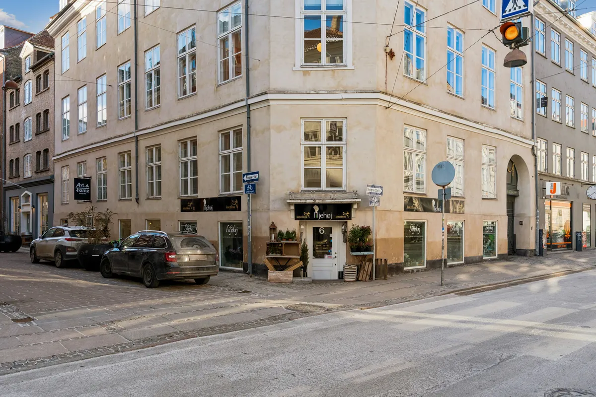 Kontor på Rådhusstræde 6, 1466 København K, med lyse vinduer, parkerede biler og en lys vej. Bygningen har et gult facade, vinduer og en hvid dør.