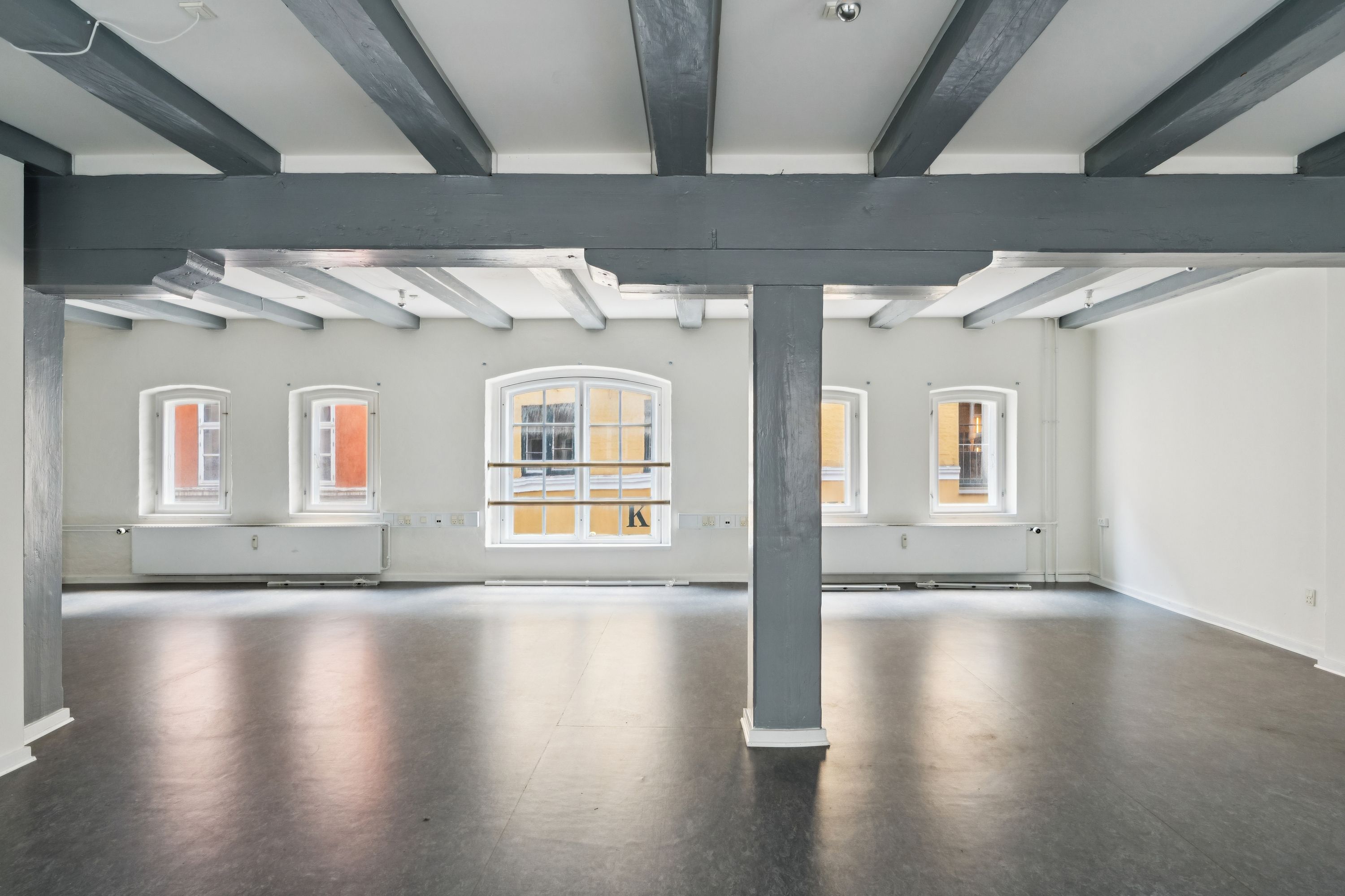 Rådhusstræde 6B, København K, kontorlokaler med højloft, tre store vinduer, moderne gulvbelægning og lyse vægge. En stor søjle i midten af lokalet.