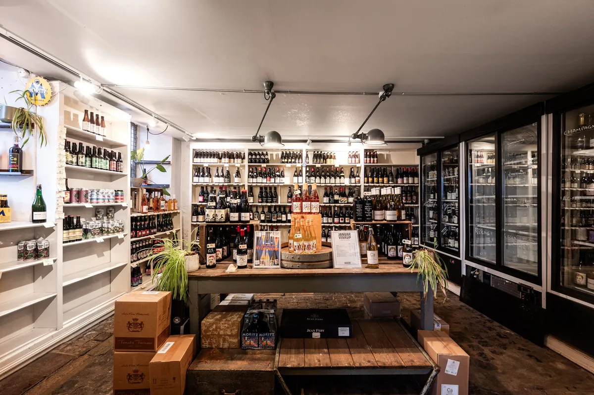 En butik med rækker af alkoholske drikkevarer og køleskabe, hvor borde og skuffer er fyldt med bokse og plantepotte
