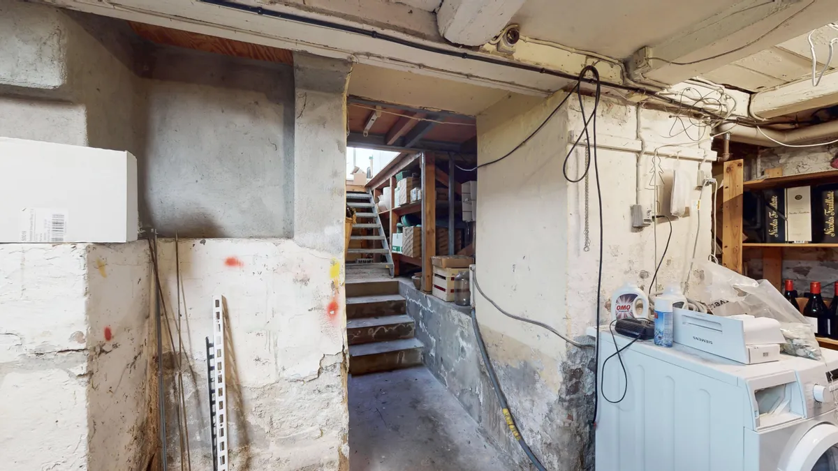 Underet i et lille rum med trætrapper og vasketøj, flere kasselagre og emballage i et lille rum med trægulve og en skråtag