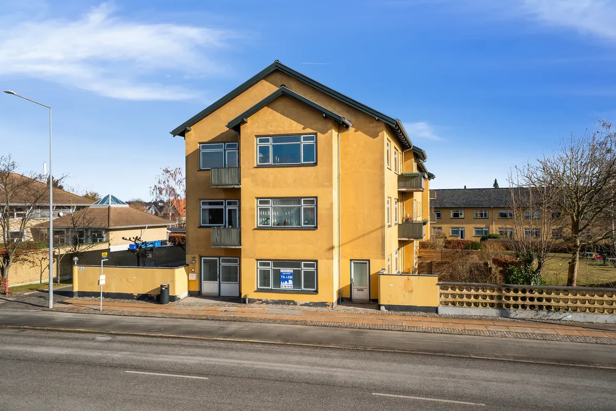 Kontor til leje på Bernstorffsvej 146 i Hellerup. Gult lejemål med balkoner og solrig udsigt. Området omgivet af grønne træer og buske.