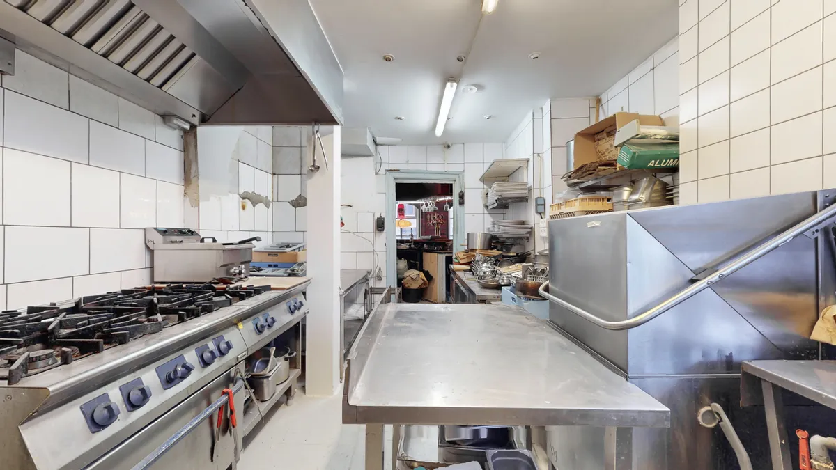 Et stort og moderne kommercielt køkken med en stor ovn, en komfur og en større stålbænk med en udtræksbar håndtag