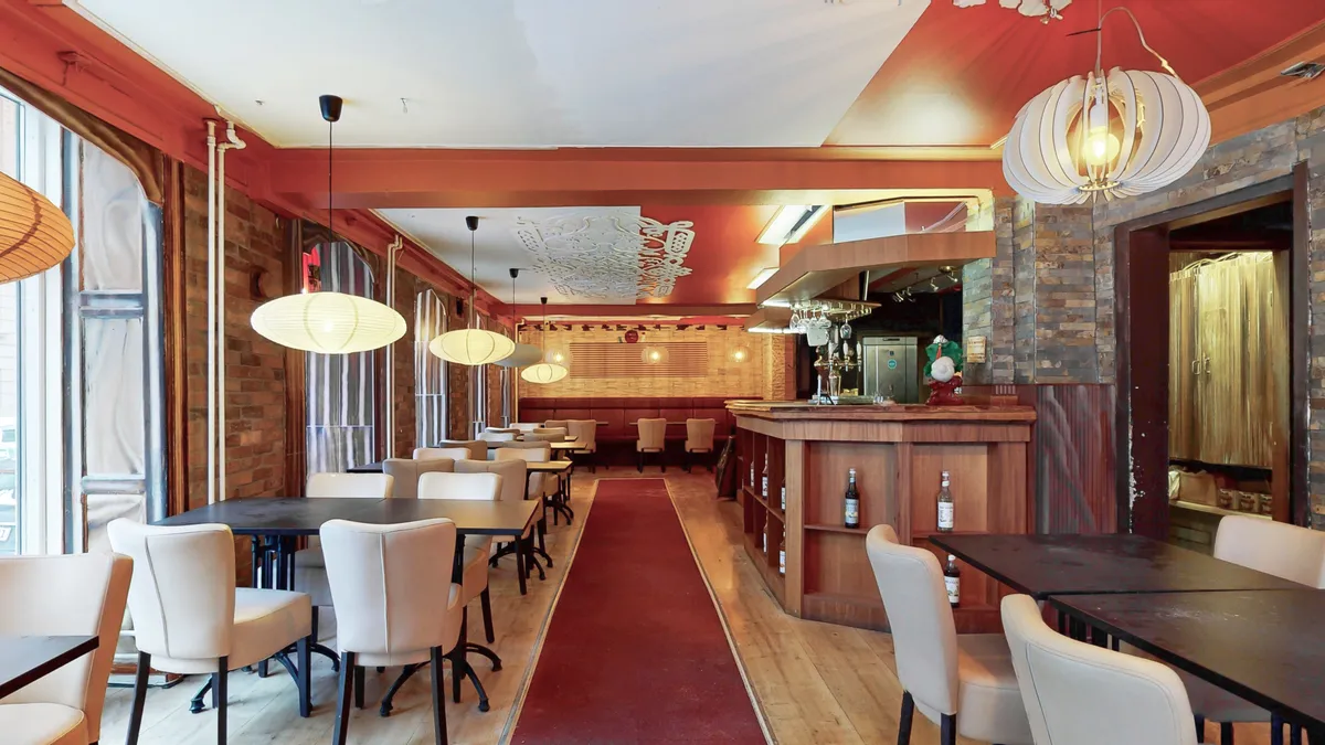 Rummeligt restaurantloft med lyse og hyggelige interiører, moderne møbler og store vinduer med udsigt til gaden