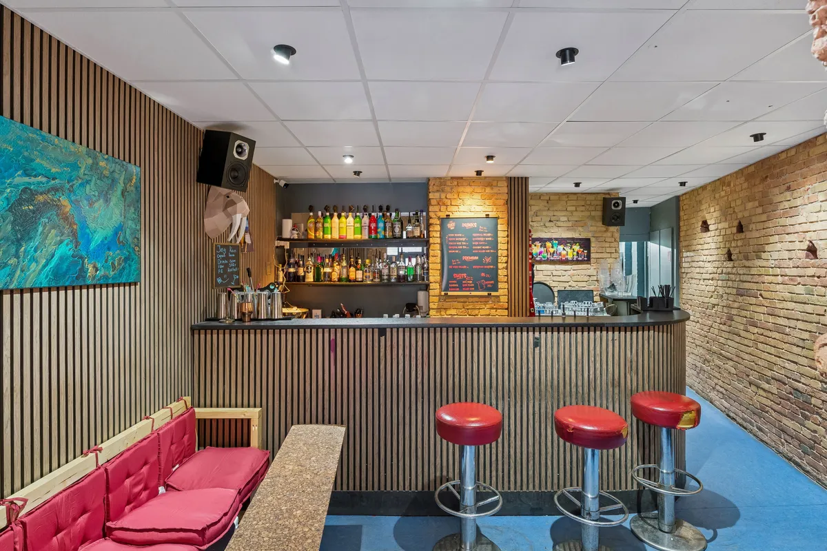 Indenfor ligger en lækker bar med røde stolene, en bardisk og udskårne sofaer samt en malet væg og udstyrede skabe med drikkevarer