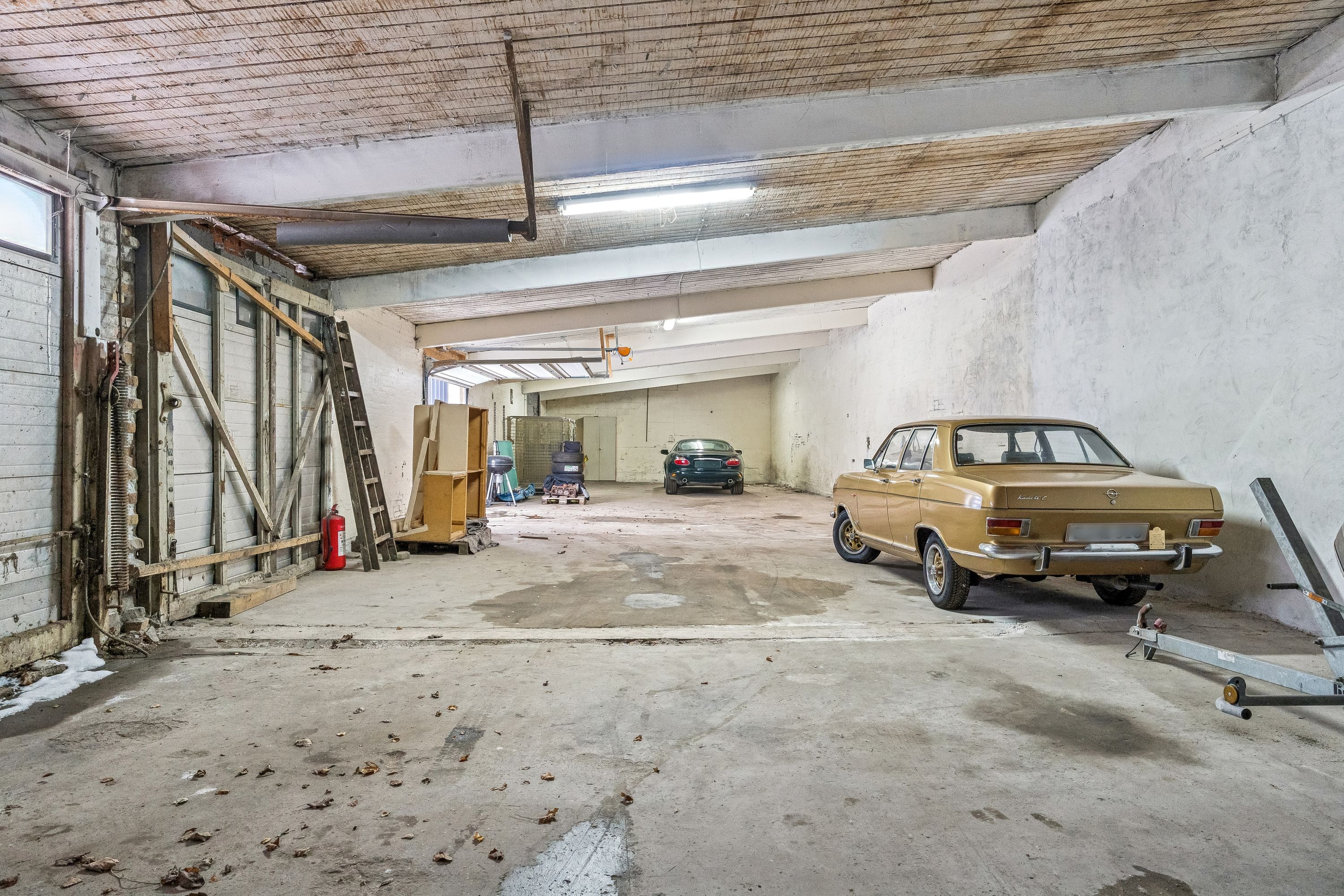 Et gammelt koldt lager med loftshøjde på 3,5 meter, to parkerede biler og to stående trapper