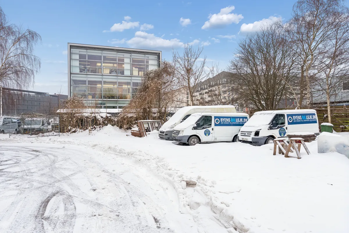 Tre hvide Byens Bil Leje biler parkeret i sne, sammen med et arbejdebord og en bænk i sne i København SV