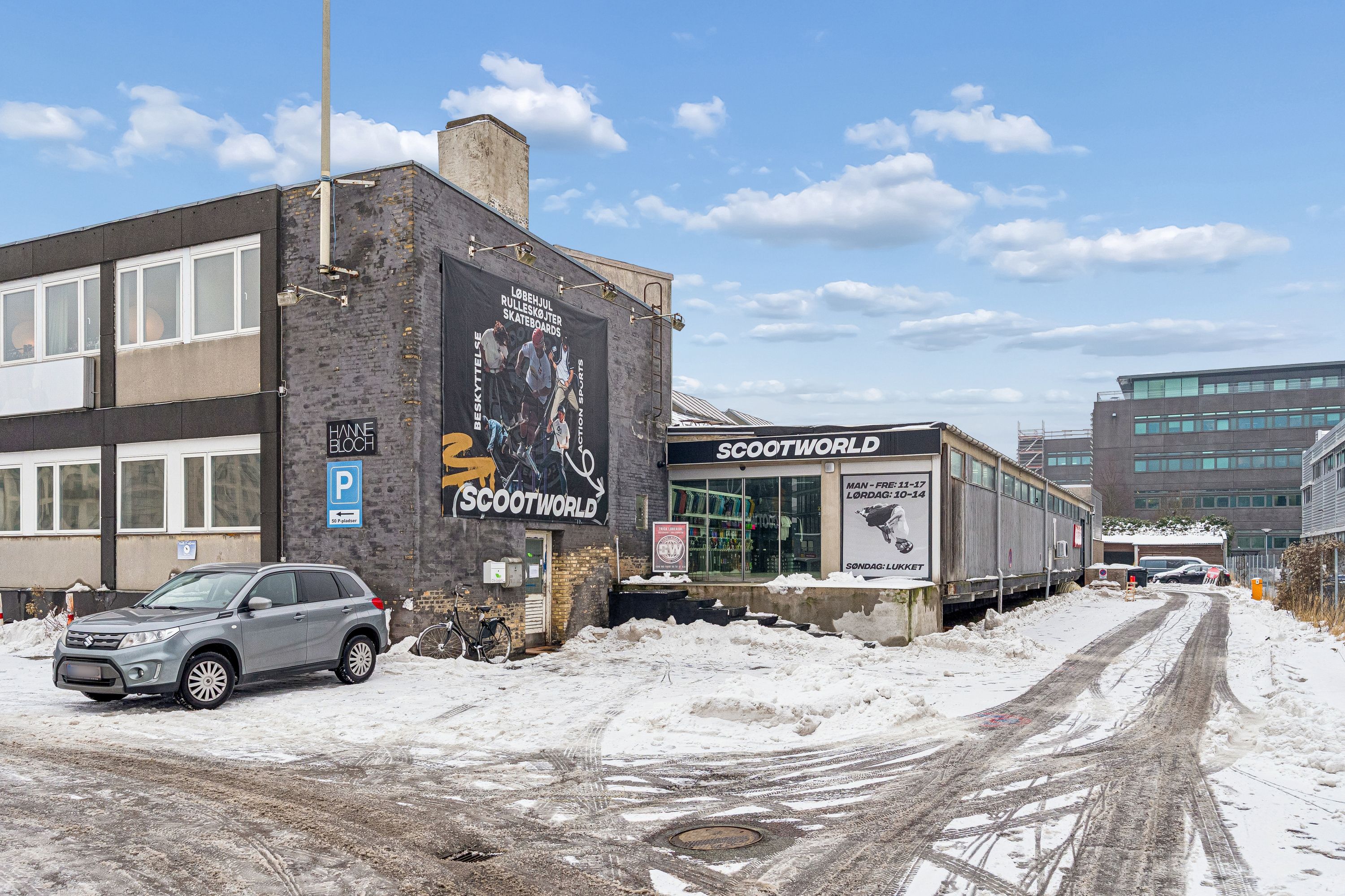 Lagerlokaler til leje i København med kælderlejemål og lejlighedsbygning i baggrunden, parkeret bil og sne dækker vejen og jorden
