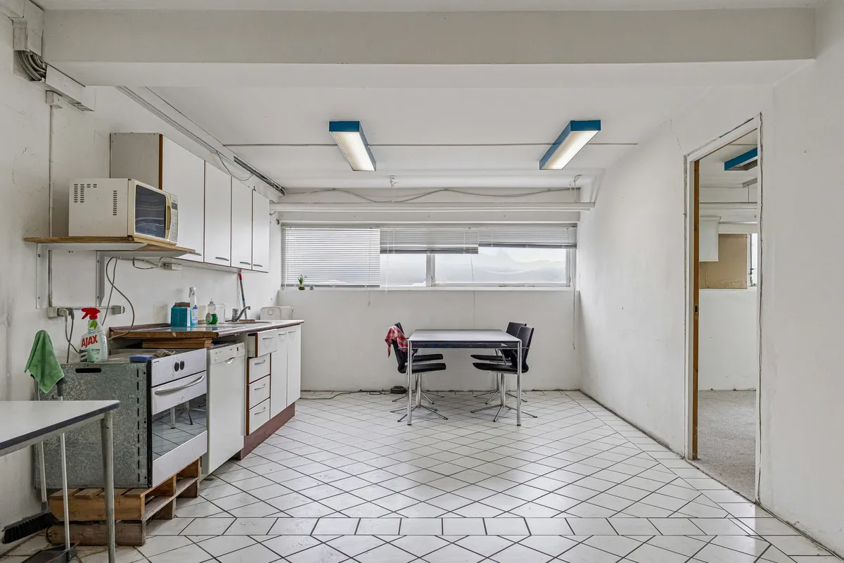 Lyst kælderlejemål med højt loft og køkken med ovn og mikrobølgeovn på Bådehavnsgade i København SV. Funktionelt køkken med bord og stole samt opvaskemaskine.