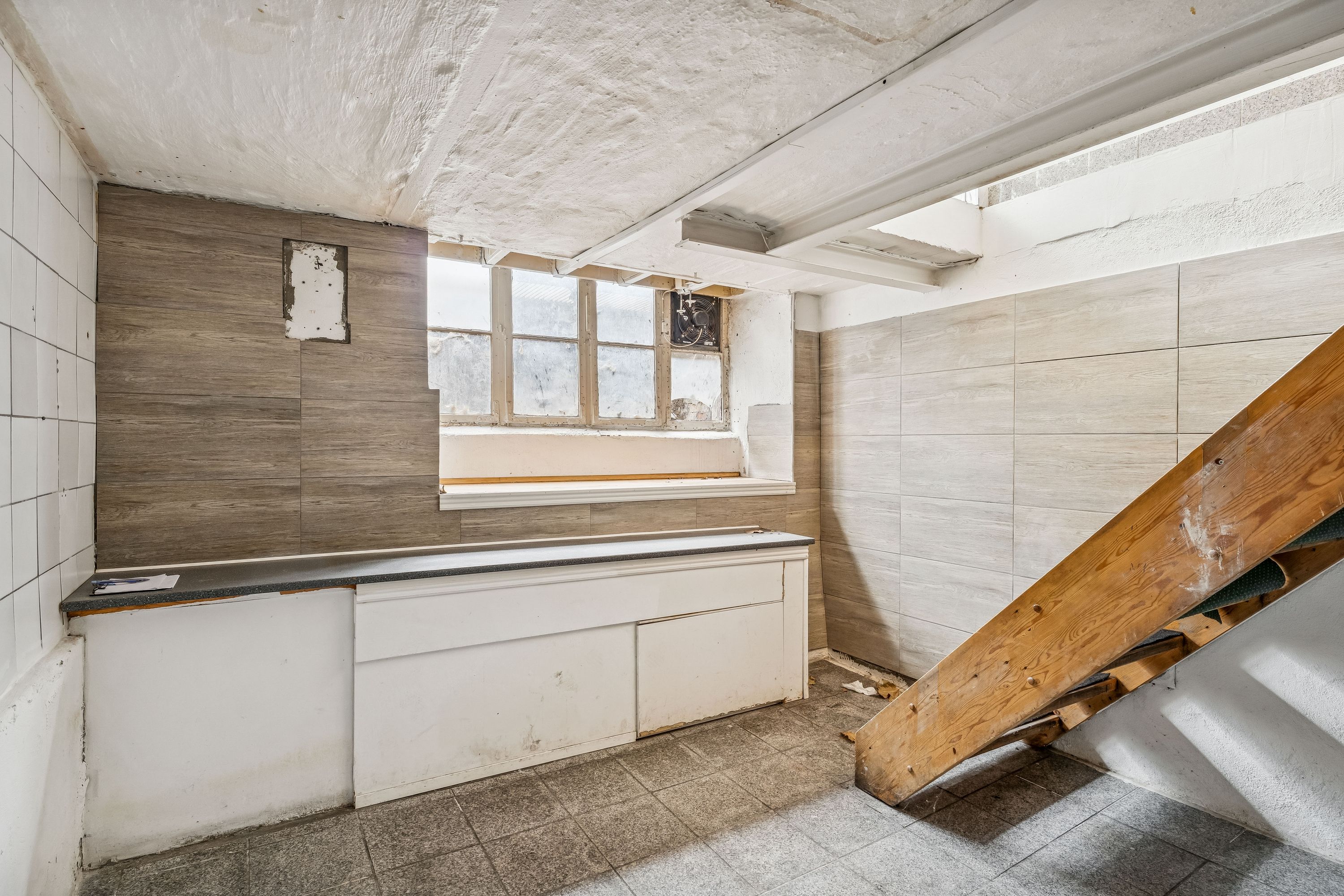 Butikslokaler til leje på Østerbrogade i København Ø. Lokalerne har højloft og vinduer med udsigt. Der er et køkken med hvide skabe og en trætrappe.