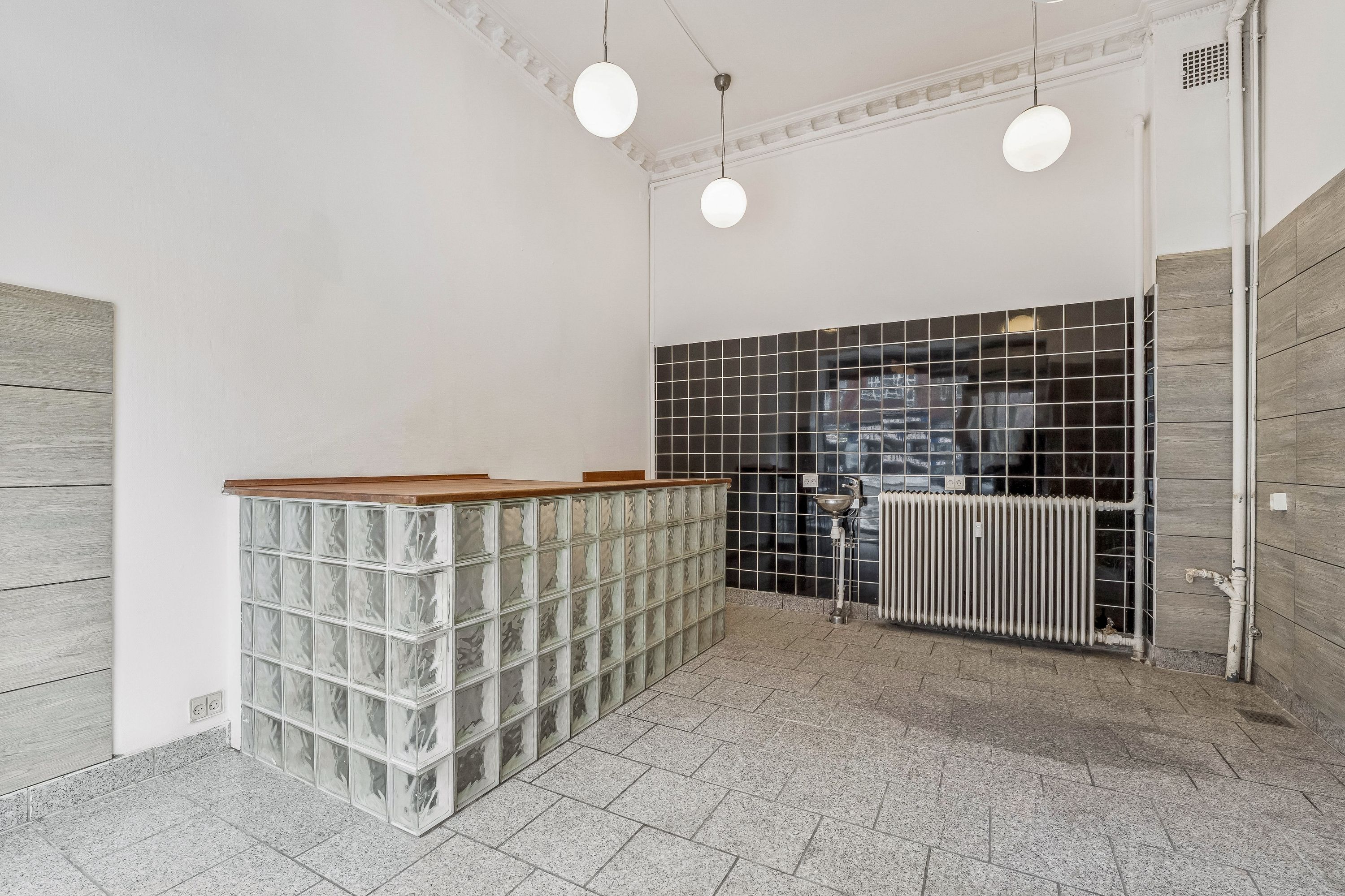 Glasblok væg og trægulv i nyt lejemål på Østerbrogade. Moderne lysekroner og radiatorer er installeret. Lejemålet er ubeboet og klar til indflytning.