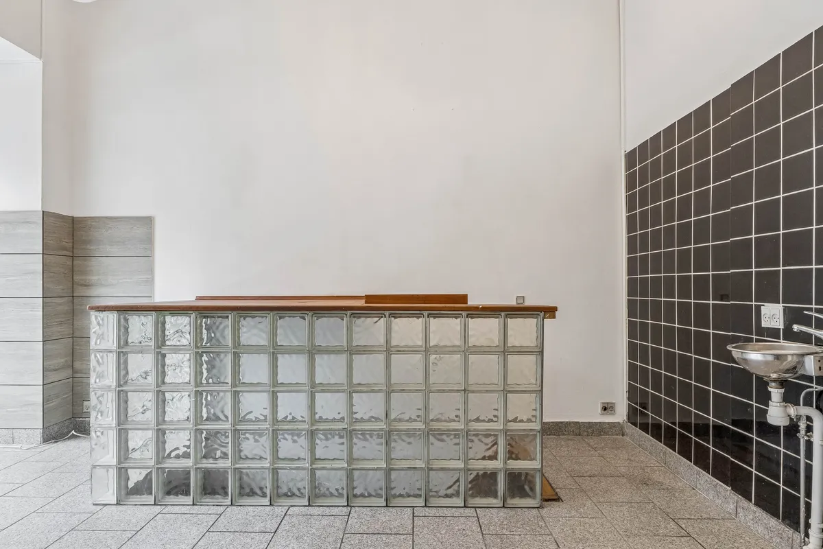 Et minimalistisk design med et gulvmonteret skurvæg i glasblokke og en håndvask på højre side af væggen i en kommerciel indgangszone med en høj synlighed på Østerbrogade