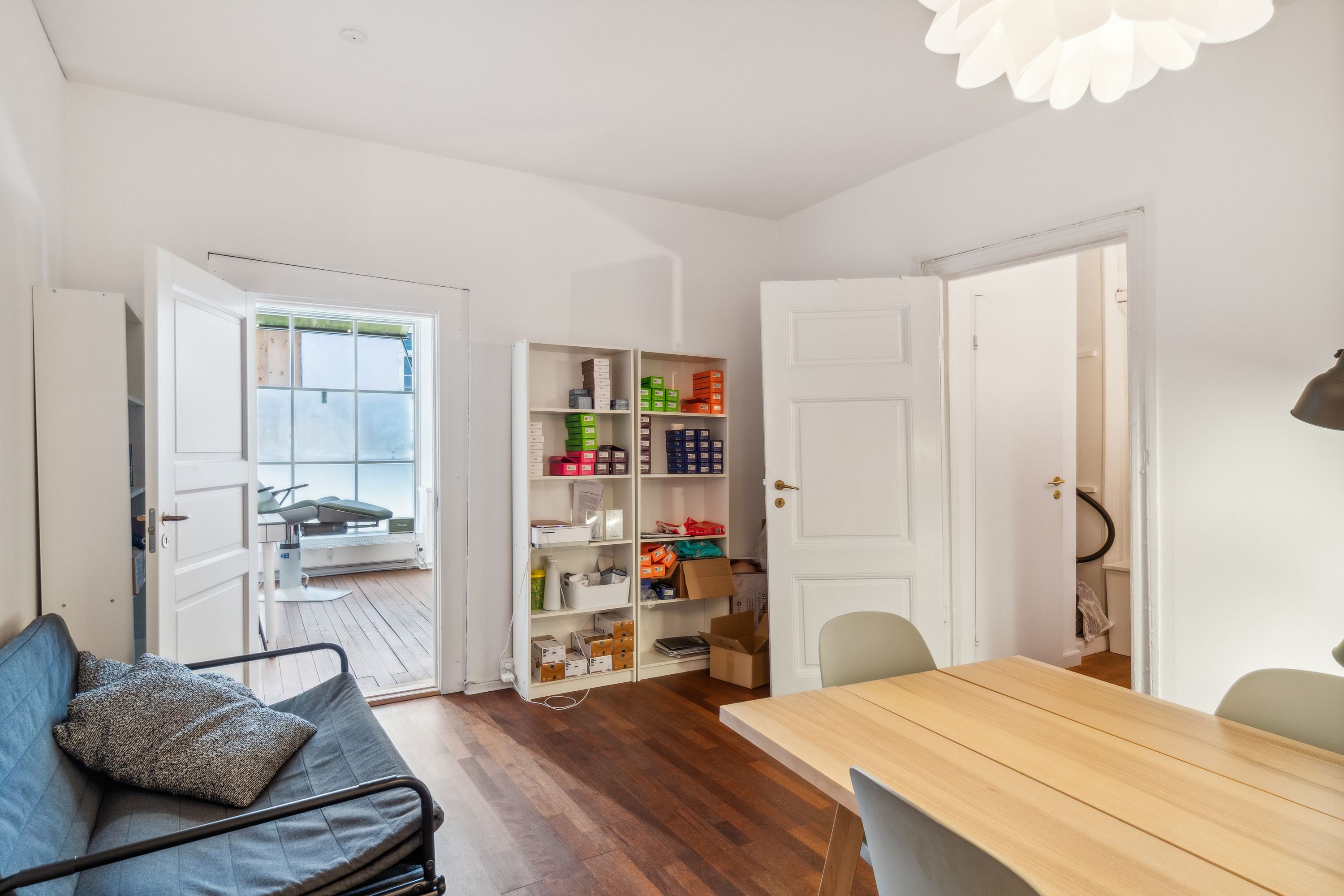 Lyst og ryddeligt kontor med sofa, skrivebord og lyse gulv. Komplet med moderne møbler og funktionelle indretningsgenstande.