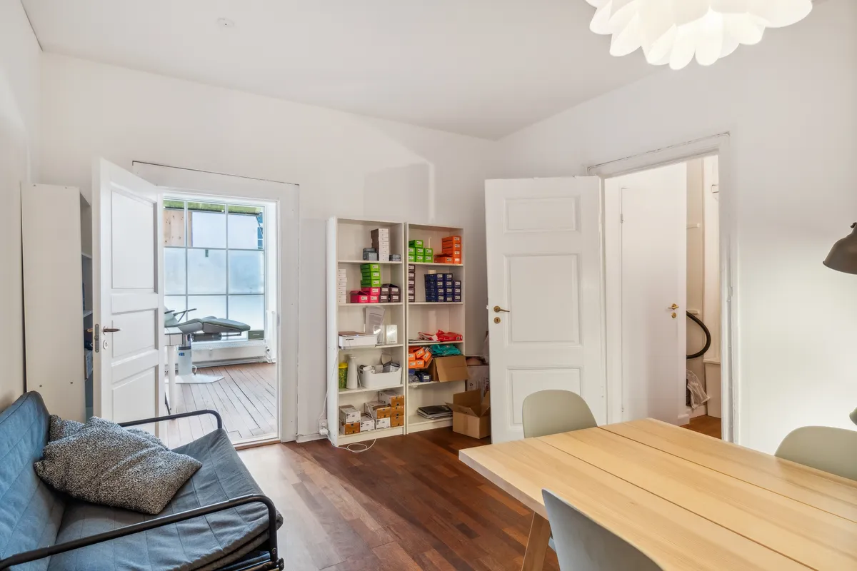 Lyst og ryddeligt kontor med sofa, skrivebord og lyse gulv. Komplet med moderne møbler og funktionelle indretningsgenstande.