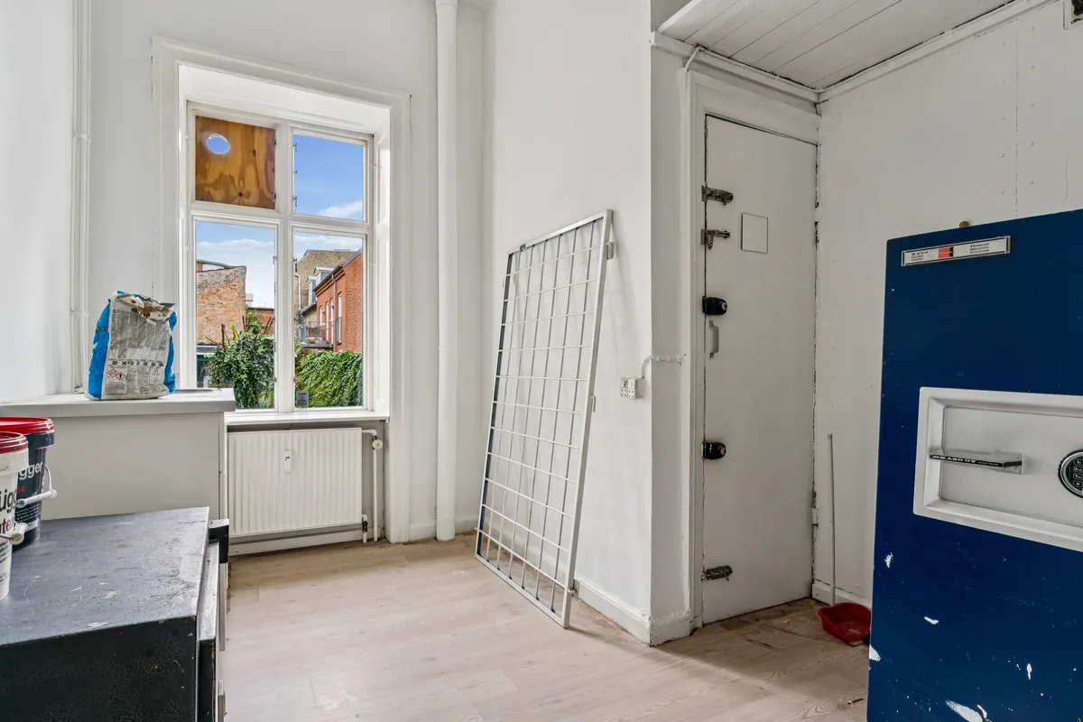 En stor, lys og tom butikslokaler med vinduer og hvide vægge, lukket dør og en stor, blå dør til siden