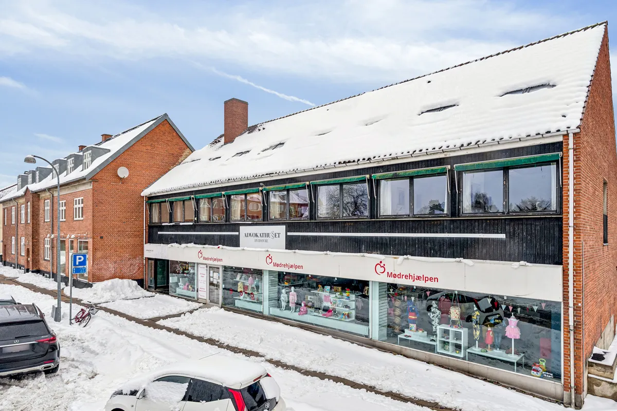 Kontorbyggeri med snedækket tag og store vinduer med udsigt til lejet butikslokaler, hyggelige butikker og caféer. Kontorer på 1. og 2. sal med udsigt over Hvidovre Torv.