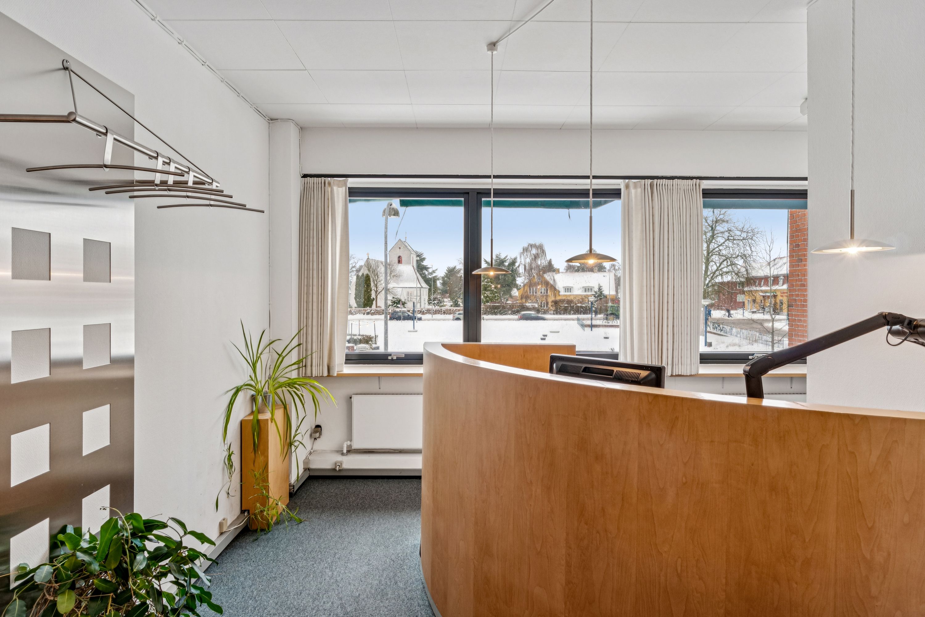 Kontor med udsigt til Hvidovre Torv, hvor der er en slank stolpe med en plante og en udsigt udenfor, hvor der er sne.