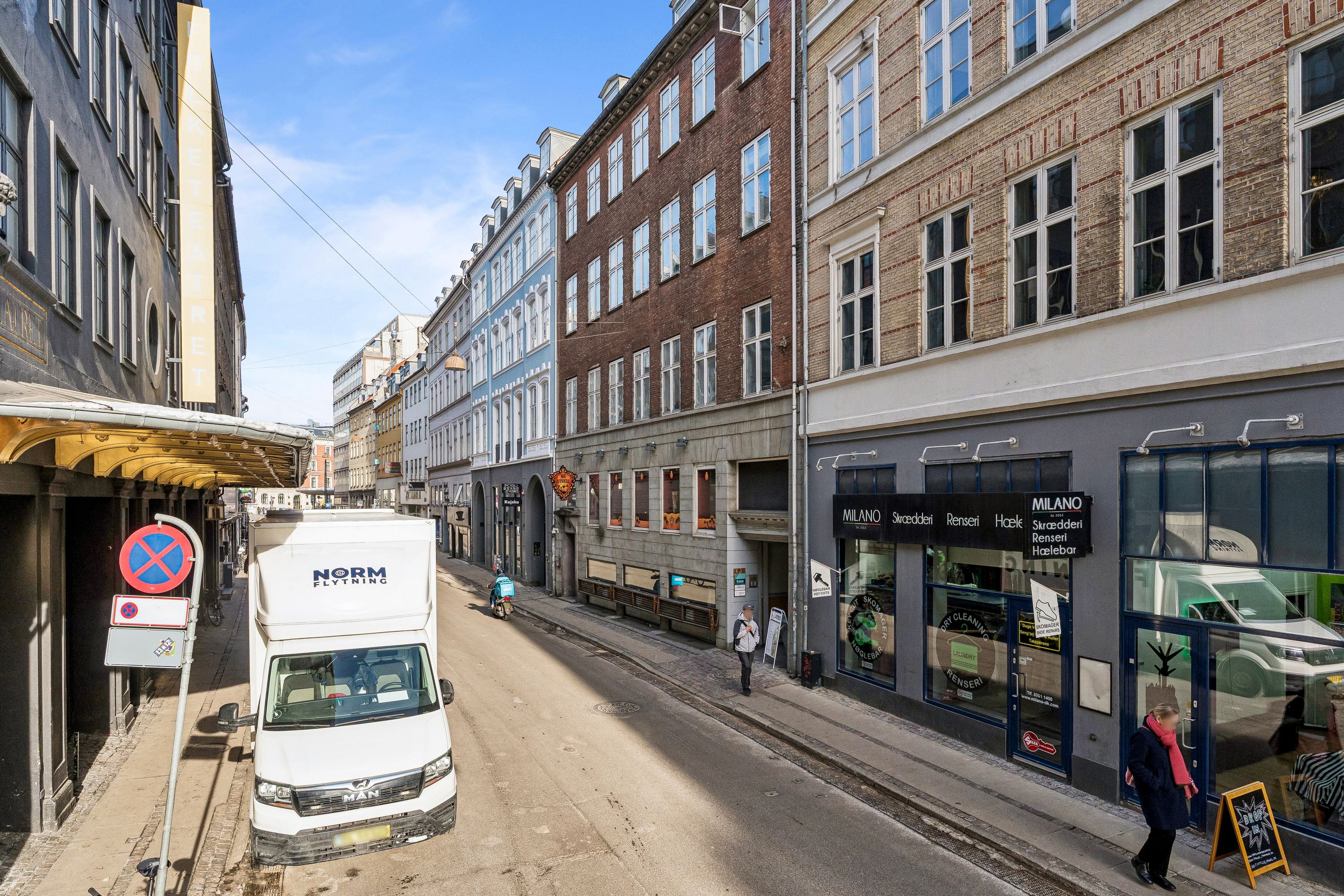 Lejemål med lyse kontorer ud mod Nørregade i København. En stor lastbil parkeret i forgrunden. En mand går forbi et Milano-skilt på en bygning