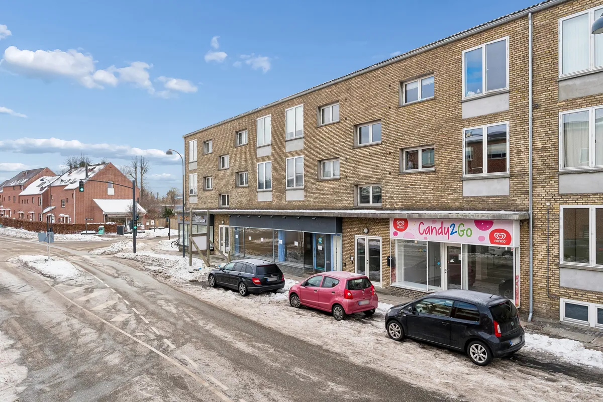 Vinterbillede med tre parkerede biler og en bygning med en Candy2Go-butik, der ligger i Gentofte på Snogegårdsvej 3.