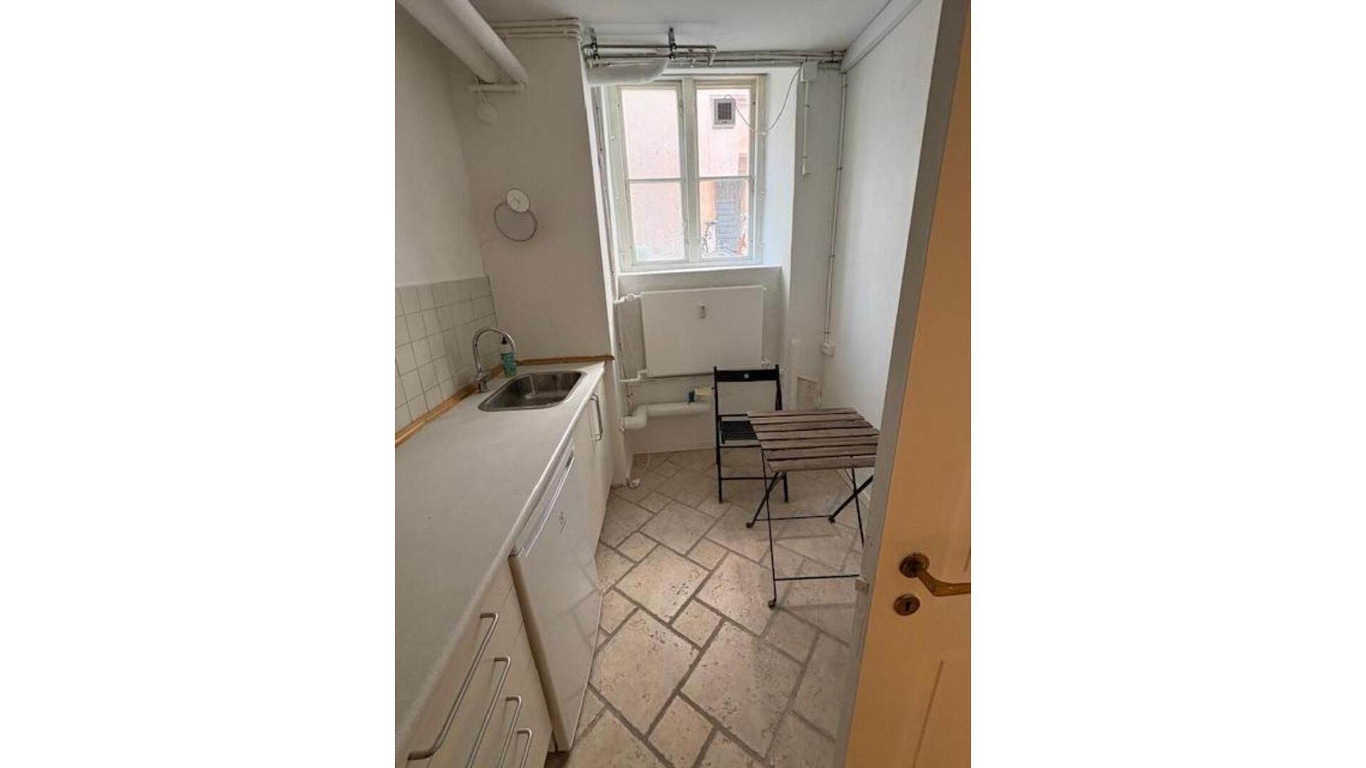 Kontor med hvidt loft og vægge, radiator og vindue samt et bord og stol.