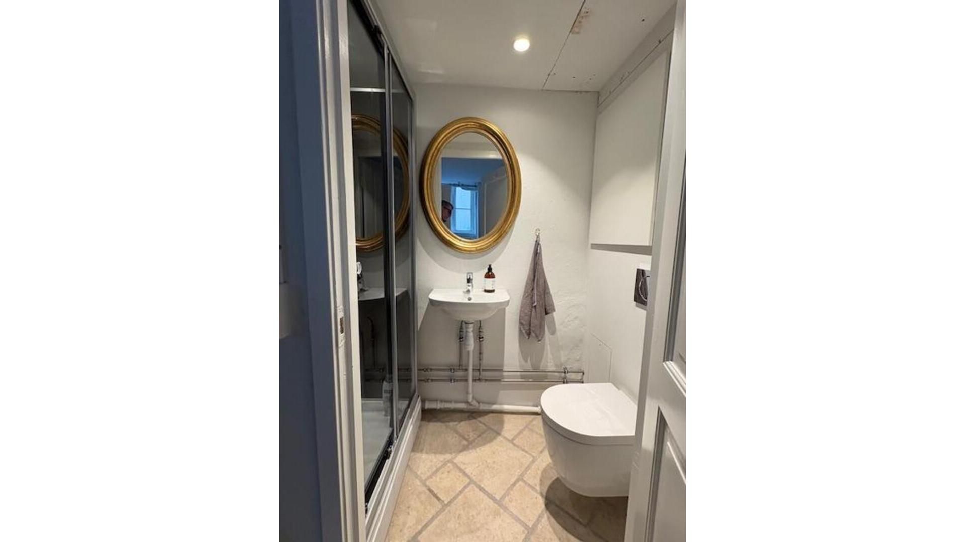 En toiletrum med hvidt toilet, håndklæde og spejl samt en hvidt badeværelse med badekar og håndklædetørrer