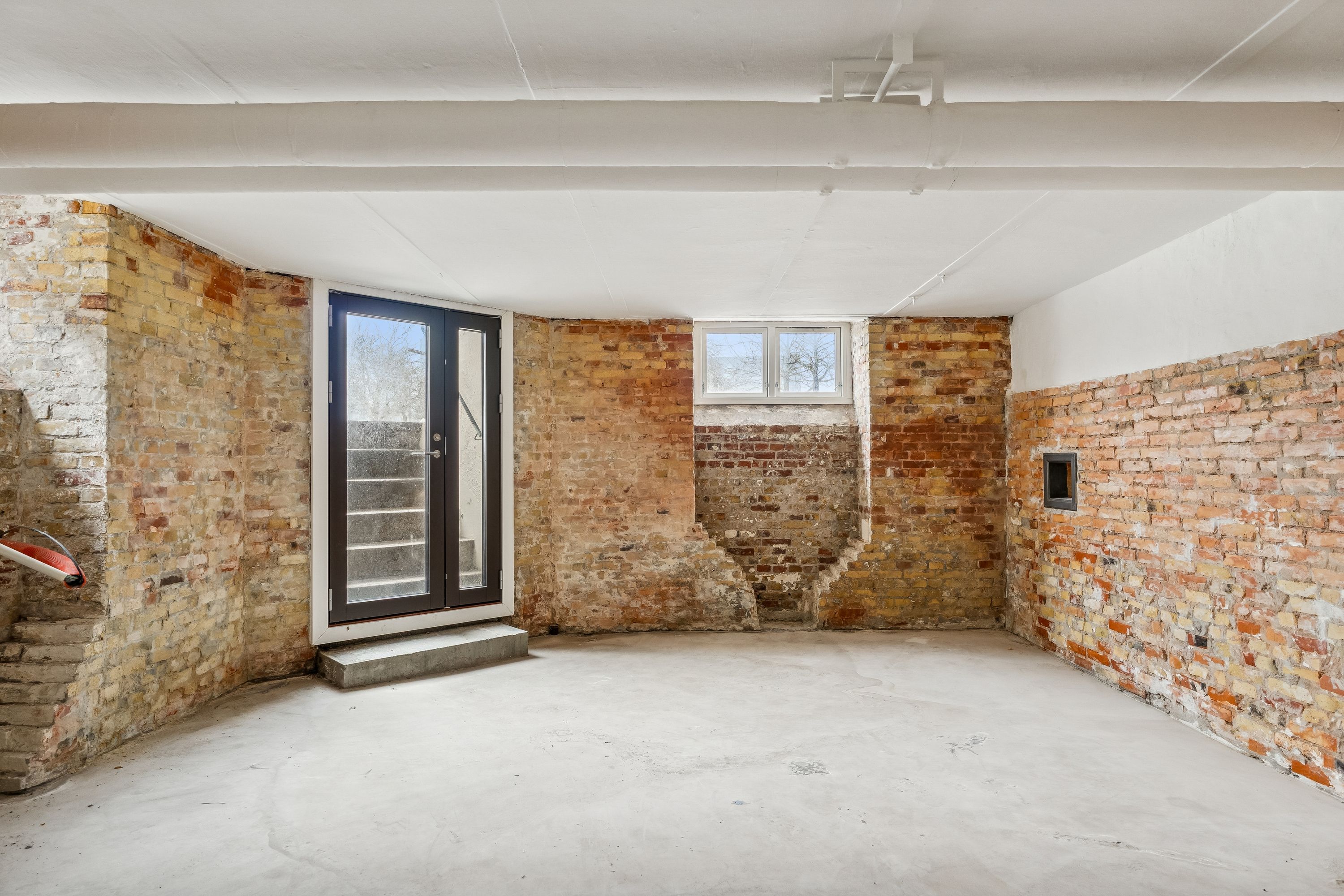 Lager med hjørneegendom og hjørneindgang. Rådighed med glasdøre og vinduer. Murene er lavet af mursten og der er hvid gulvbelægning.