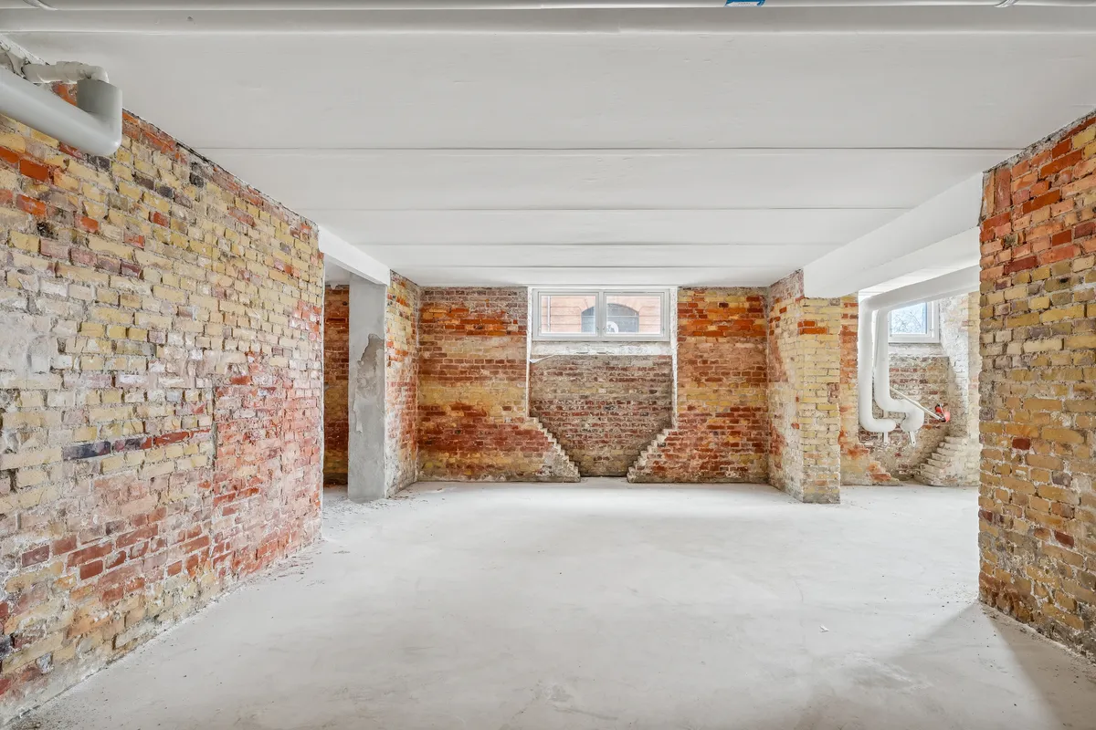 Lager med hjørnevindu og røde murstensvægge samt hvide loftsbjælker og en hvid gulv.