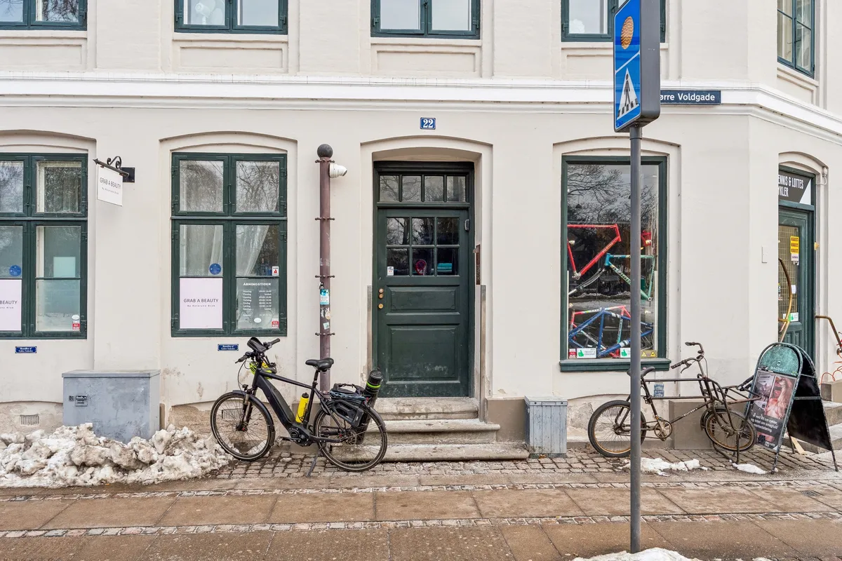 Foto af Nørre Voldgade 22 i København med udsigt til Ørstedsparken, 2 cykler foran døren og skilte med teksten Grab a Beauty og Ørre Voldgade