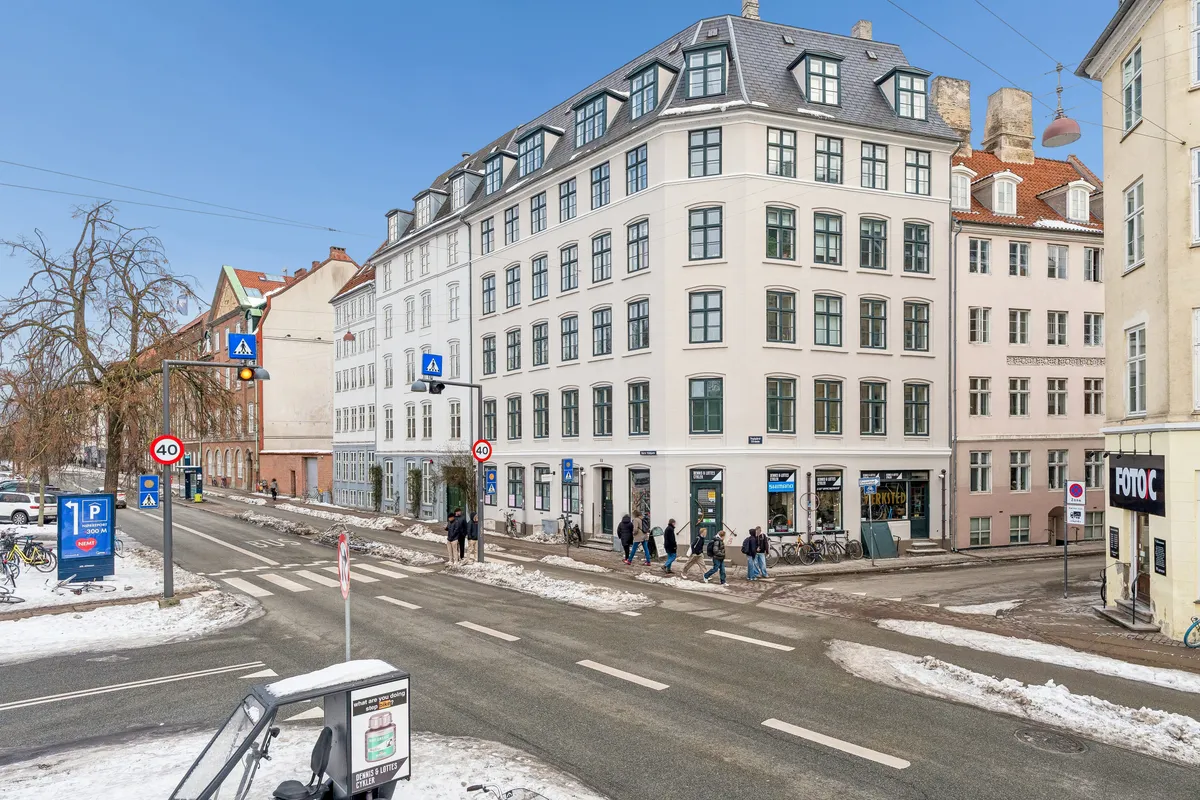 Mennesker går på gågaden med sne på vejen, 40 km/t skilt og snescooter i snedækket med bygninger og en bilparkeringsskilt