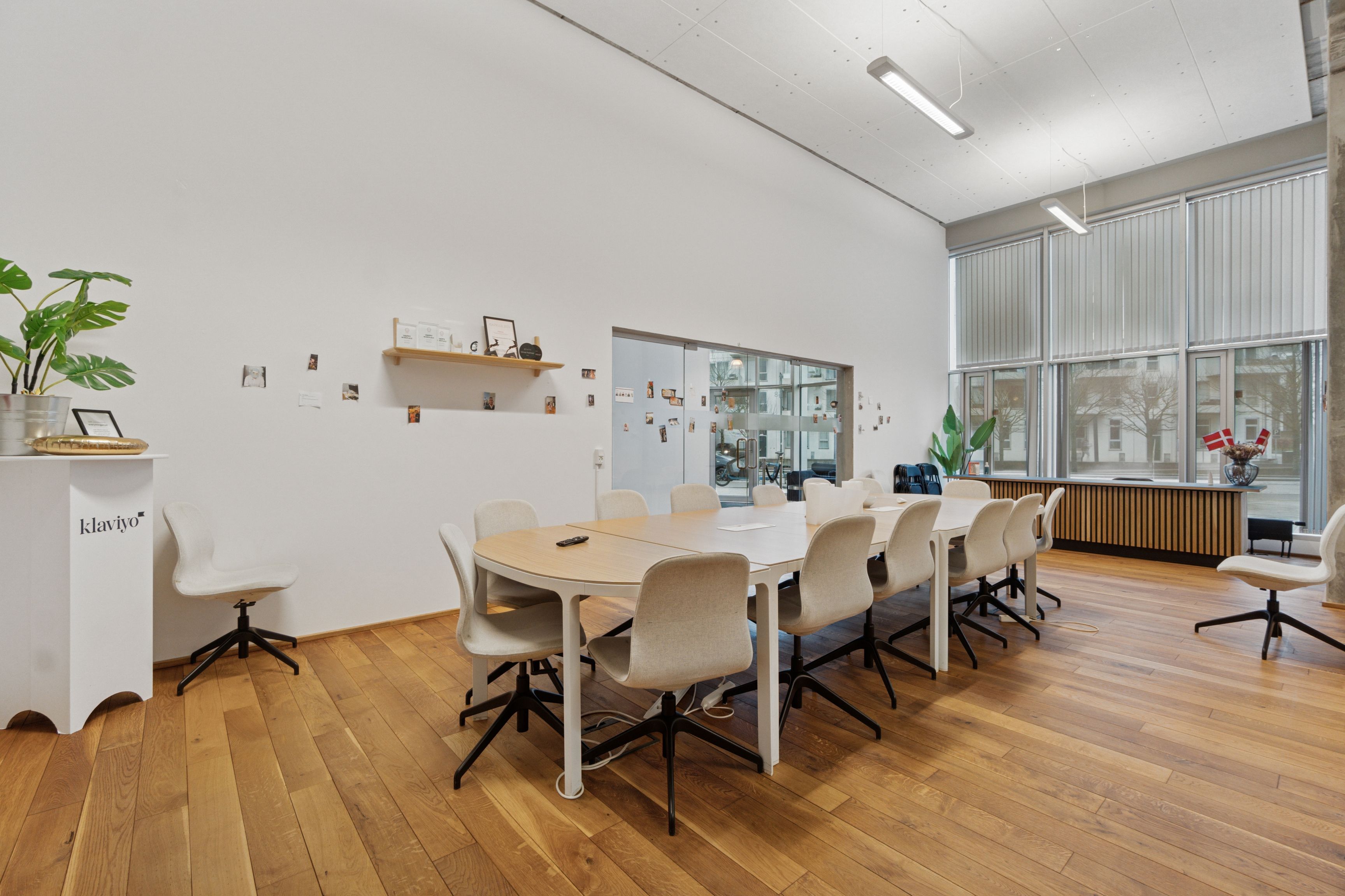 Kontorområde med to lange runde borde og høje vinduer mod gaden og bygningen udenfor