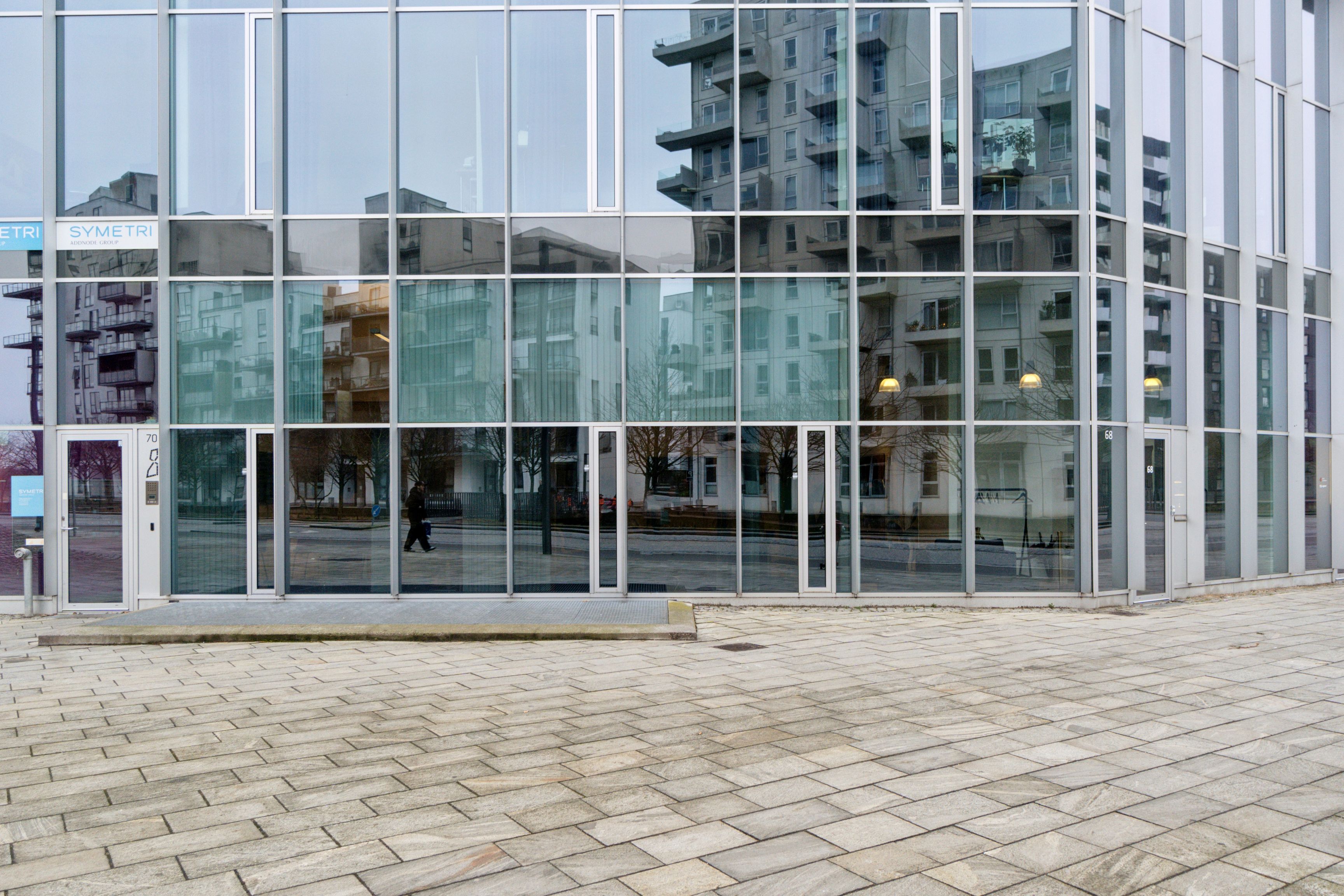 Moderne glas facade med indgangsdøre og Symtri logo, tæt på Ørestad metrostation, kontorlejemål i København med flotte og lyse rum