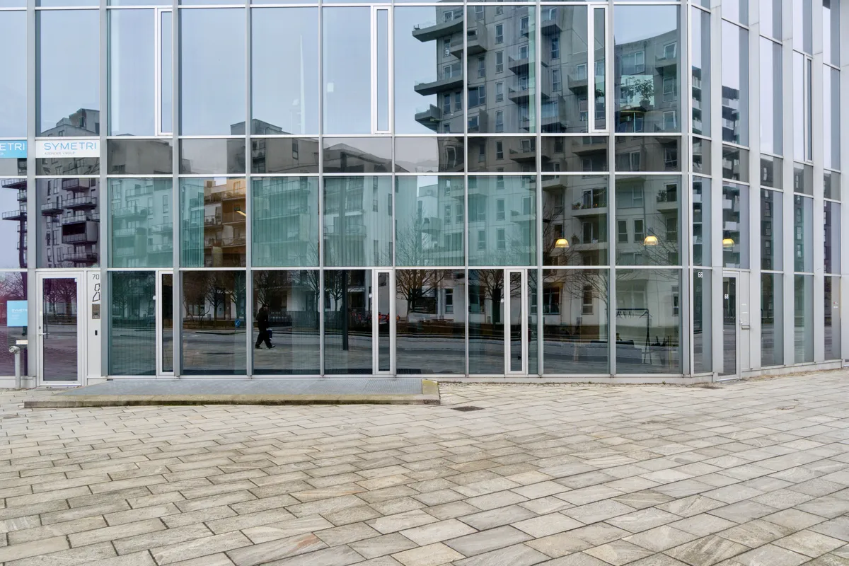 Moderne glas facade med indgangsdøre og Symtri logo, tæt på Ørestad metrostation, kontorlejemål i København med flotte og lyse rum