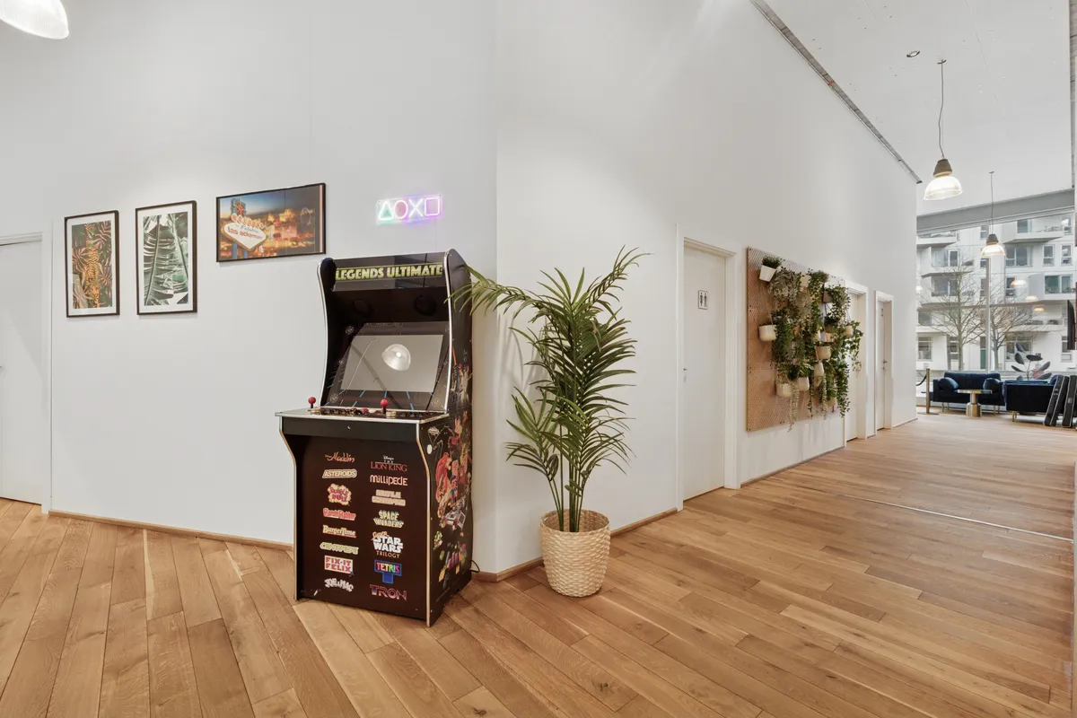 Moderne kontorlejemål med spillemaskine og lysekroner på loftet og plante i kurv på gulvet