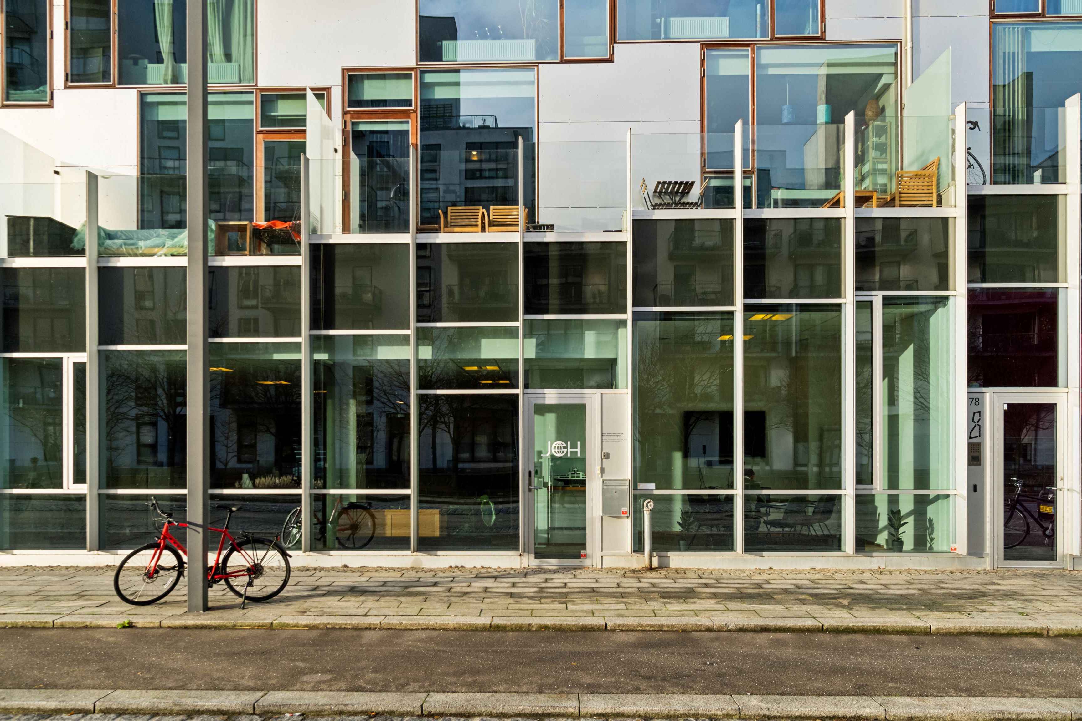 En lys og indbydende kontorlejemål i Ørestad med store vinduer og en parkeringsplads med en rød cykel