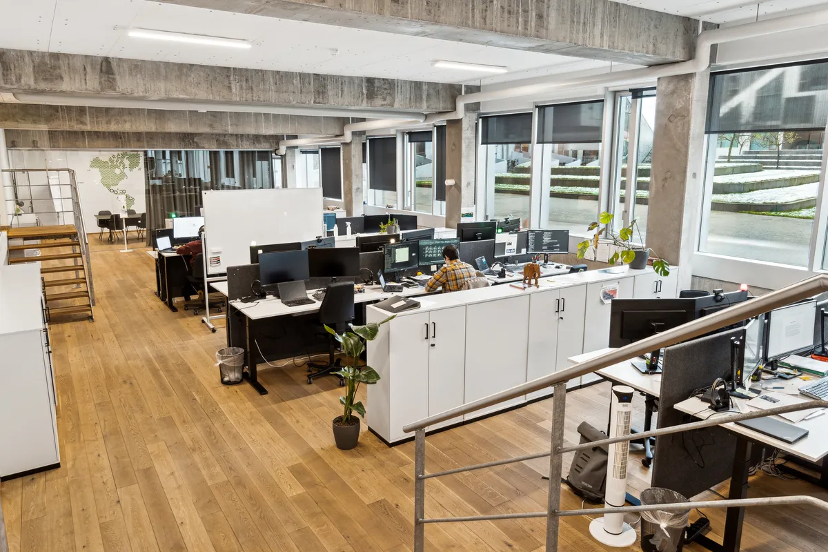 Kontorlejemål i Ørestad med lyse gulve, hvide vægge og moderne møbler. Planter og teknologi er synlige. Steder til samarbejde og privat arbejde. Lyst og indbydende atmosfære.