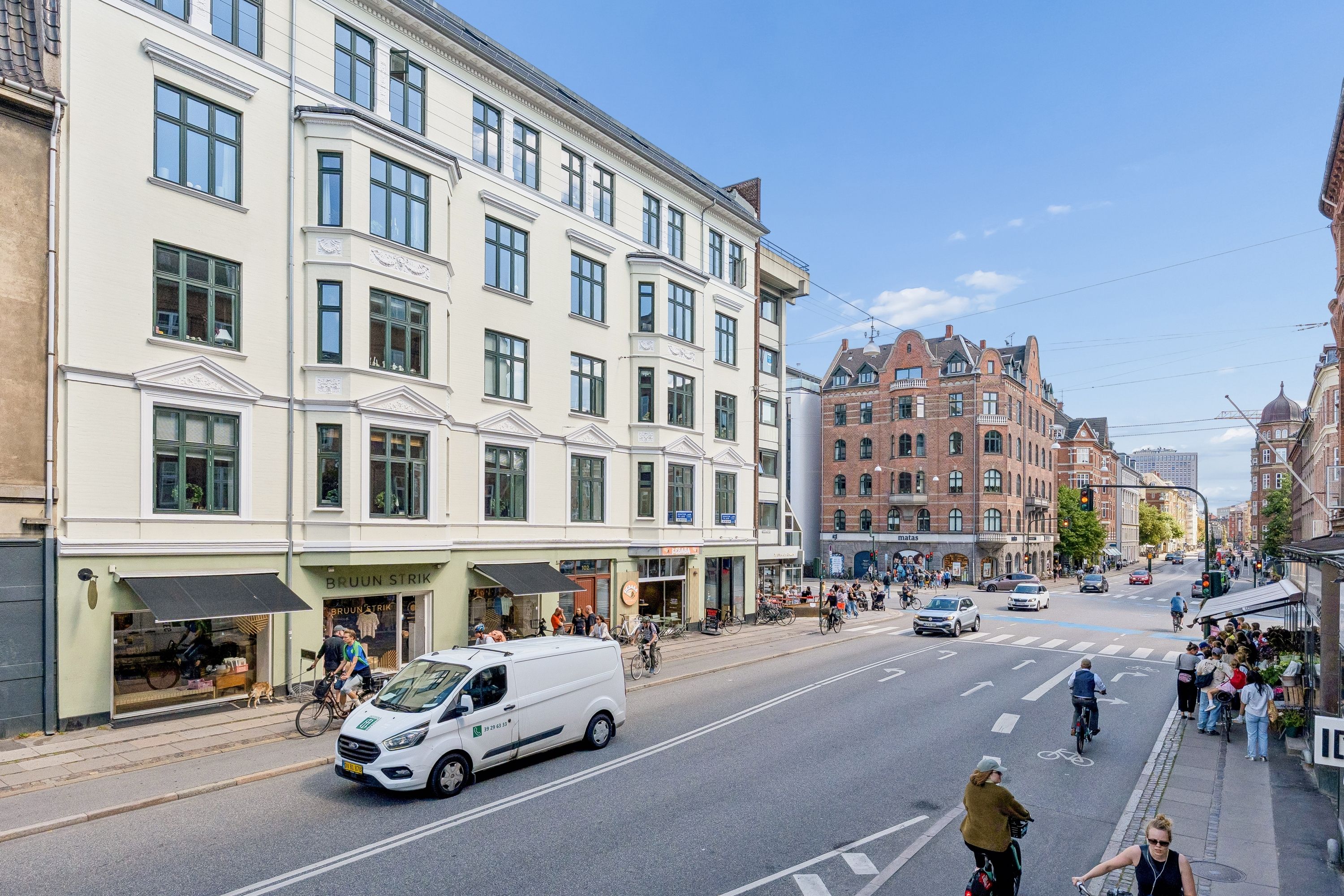 Mange mennesker og cykler på Gammel Kongevej i Frederiksberg. En hvid Ford Transit van kører på vejen, og der er mange gågader og parkerede biler.