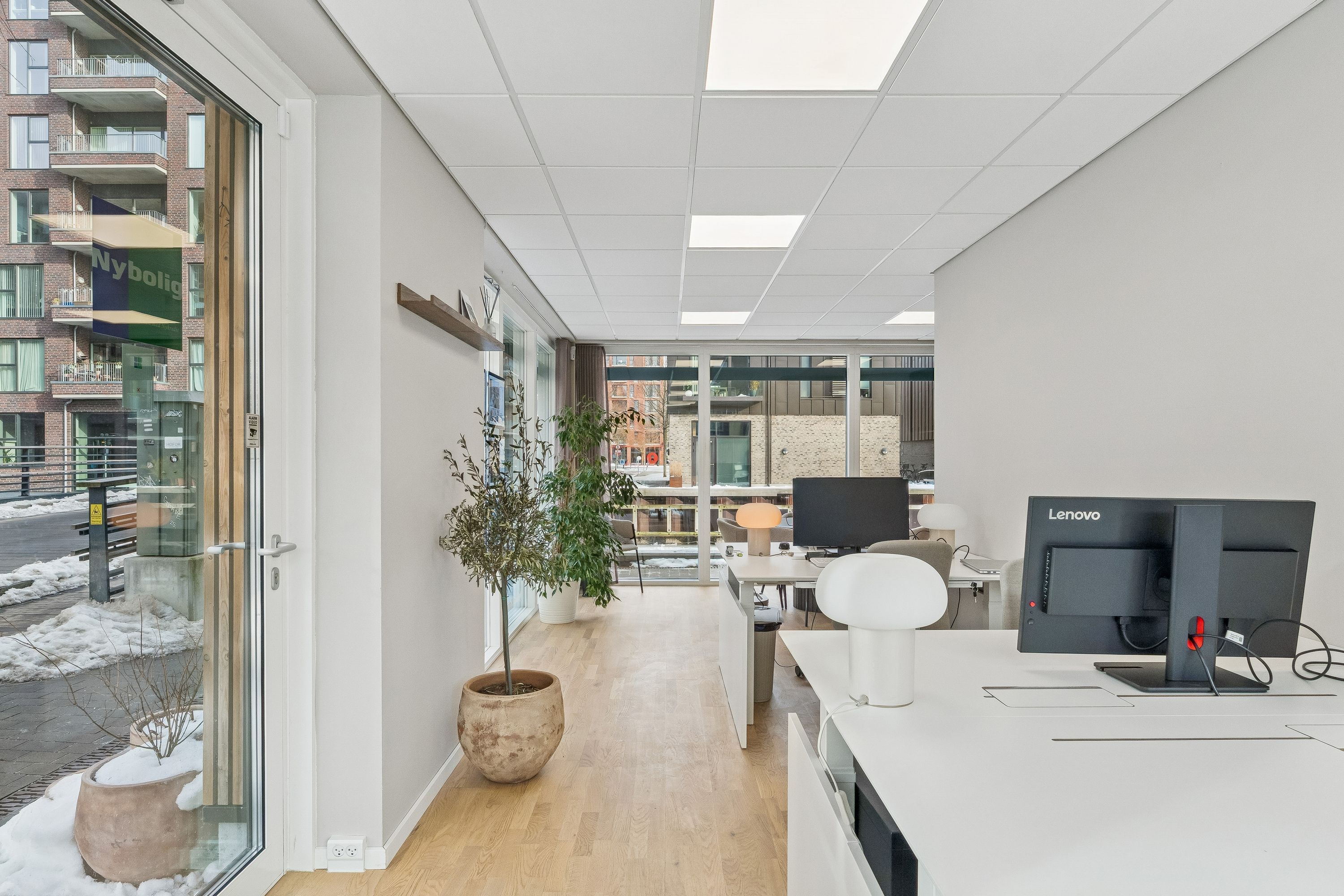 Lejlighed til leje på Teglholmens Østkaj med to store plantager og et minimalistisk kontor med moderne skrivebord, computer og lampe.