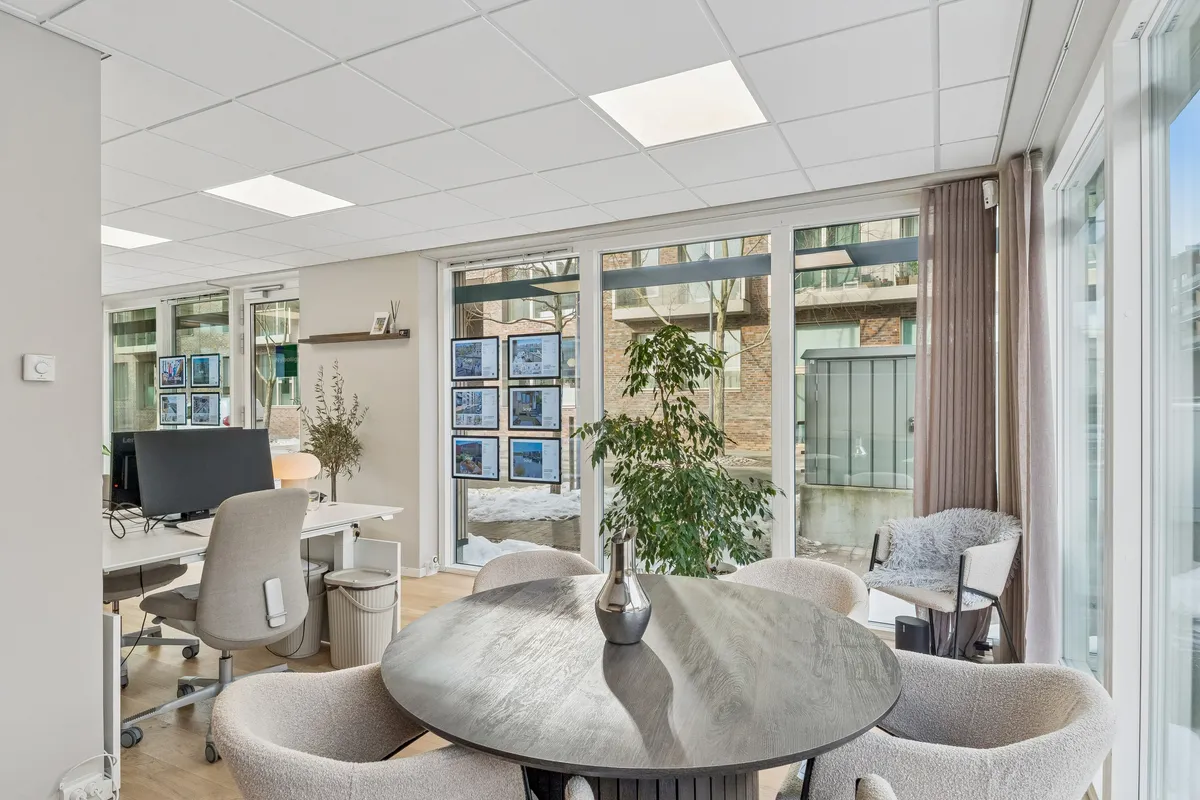 Moderne kontor med højt loft og store ruder med udsigt til byggede områder, skrivebord og stol med computer og plante