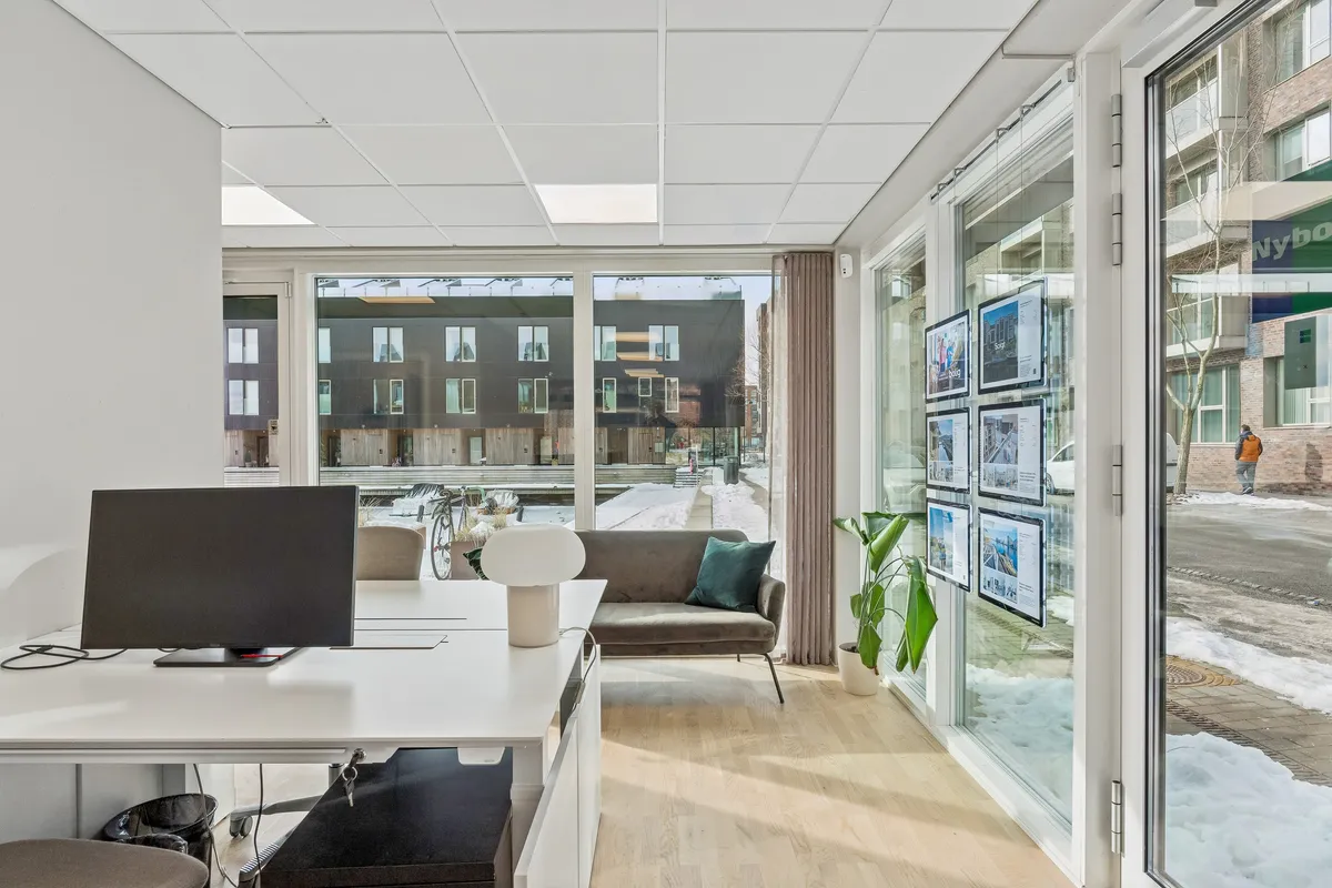 Kontor med lys og rummelige vinduer og udsigt til en snebelagt gade med grønne planter og et byggeprojekt i baggrunden