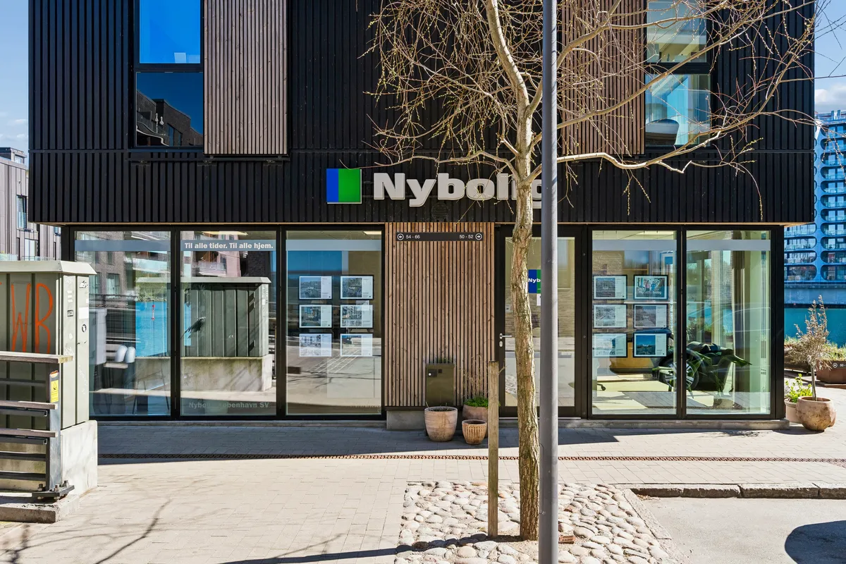 Butik til leje på Teglholmens Østkaj 50 i København SV med moderne facade og store glasvinduer, indrettet med tre store potteplanter og reklamefotos inde