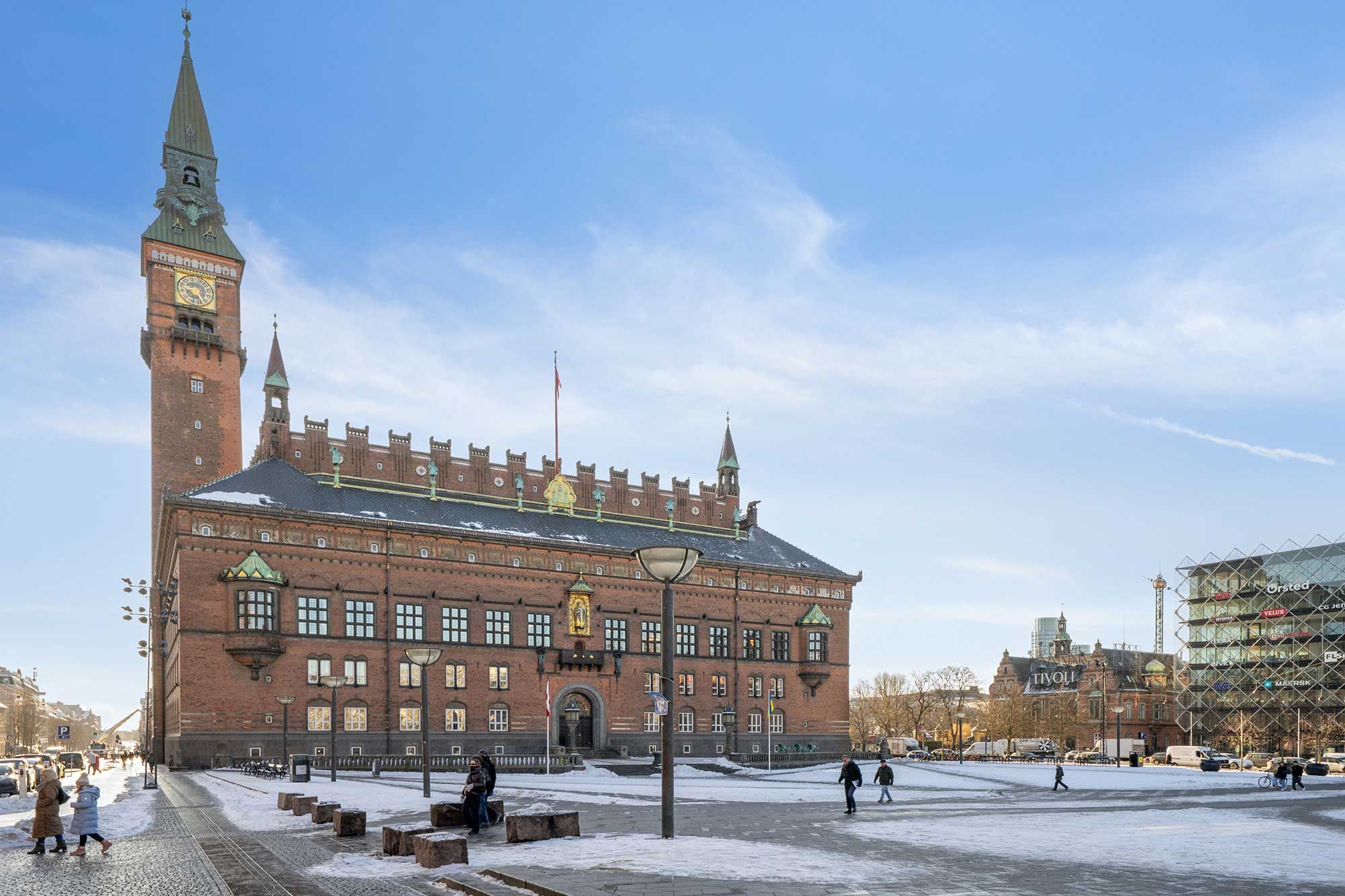 Kontorlejemål i Latinerkvarter. Historisk bygning med facaden og søjler. Folk går rundt på Christianshavns Torv. Sne på jorden og bygningen har et uret