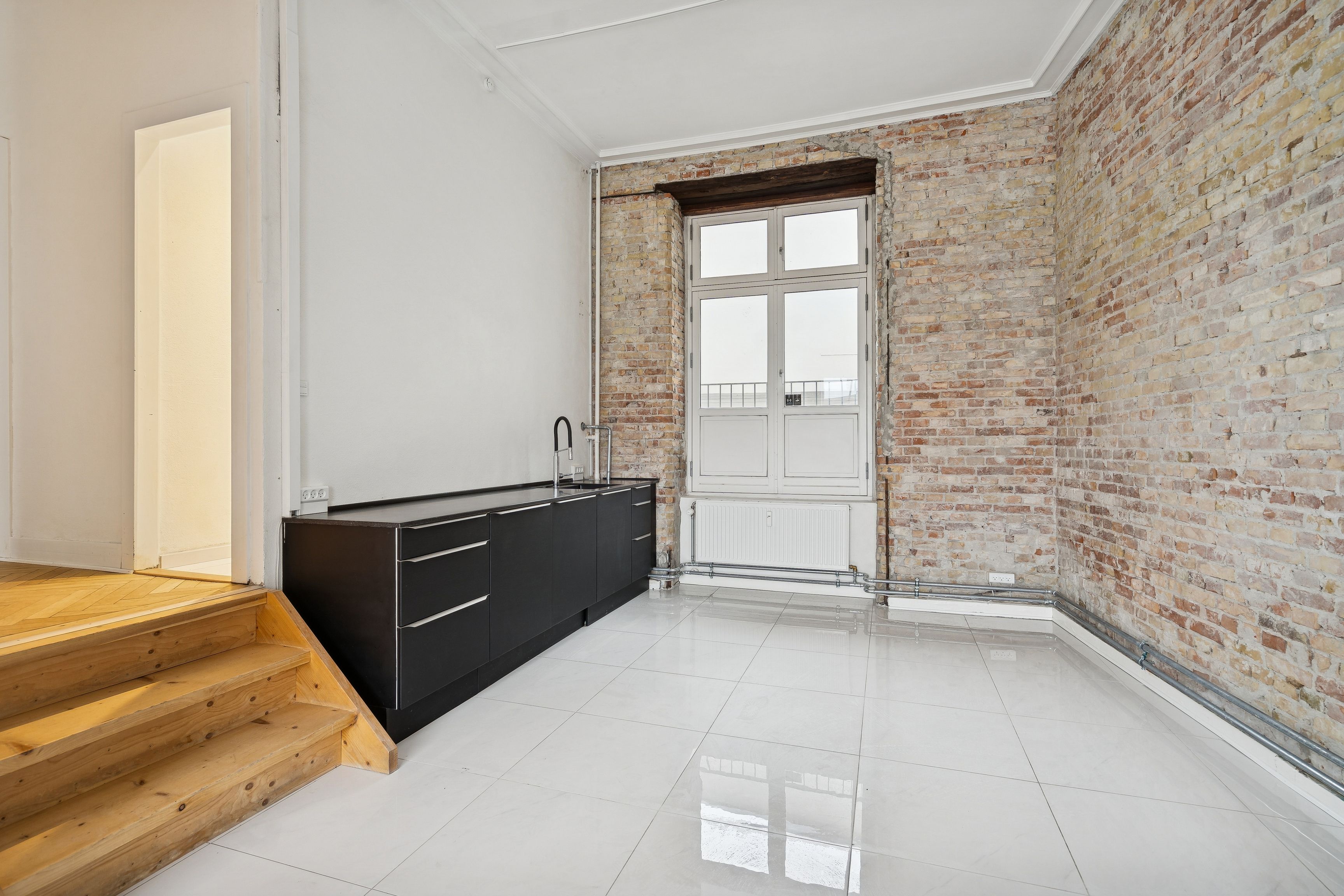 Moderne, minimalistisk køkken med hvide keramiske fliser, sort granit køkkenfront og lyse vinkler fra vinduet