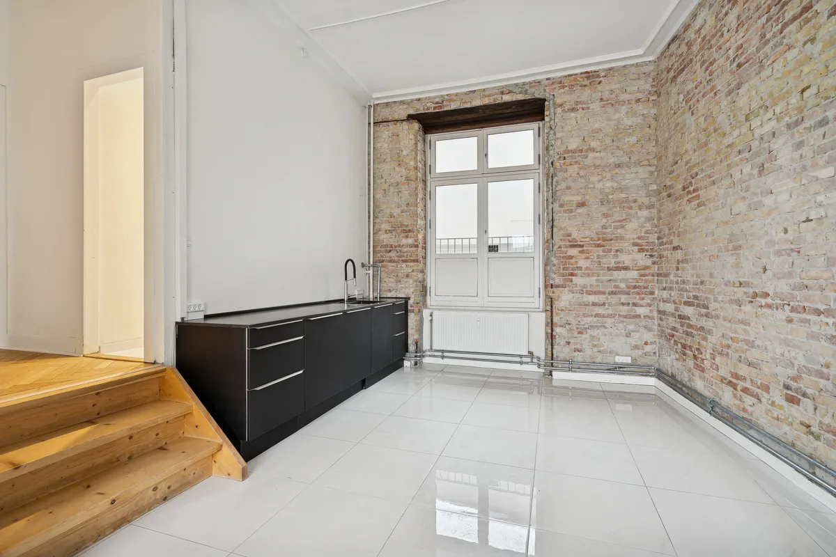 Moderne, minimalistisk køkken med hvide keramiske fliser, sort granit køkkenfront og lyse vinkler fra vinduet