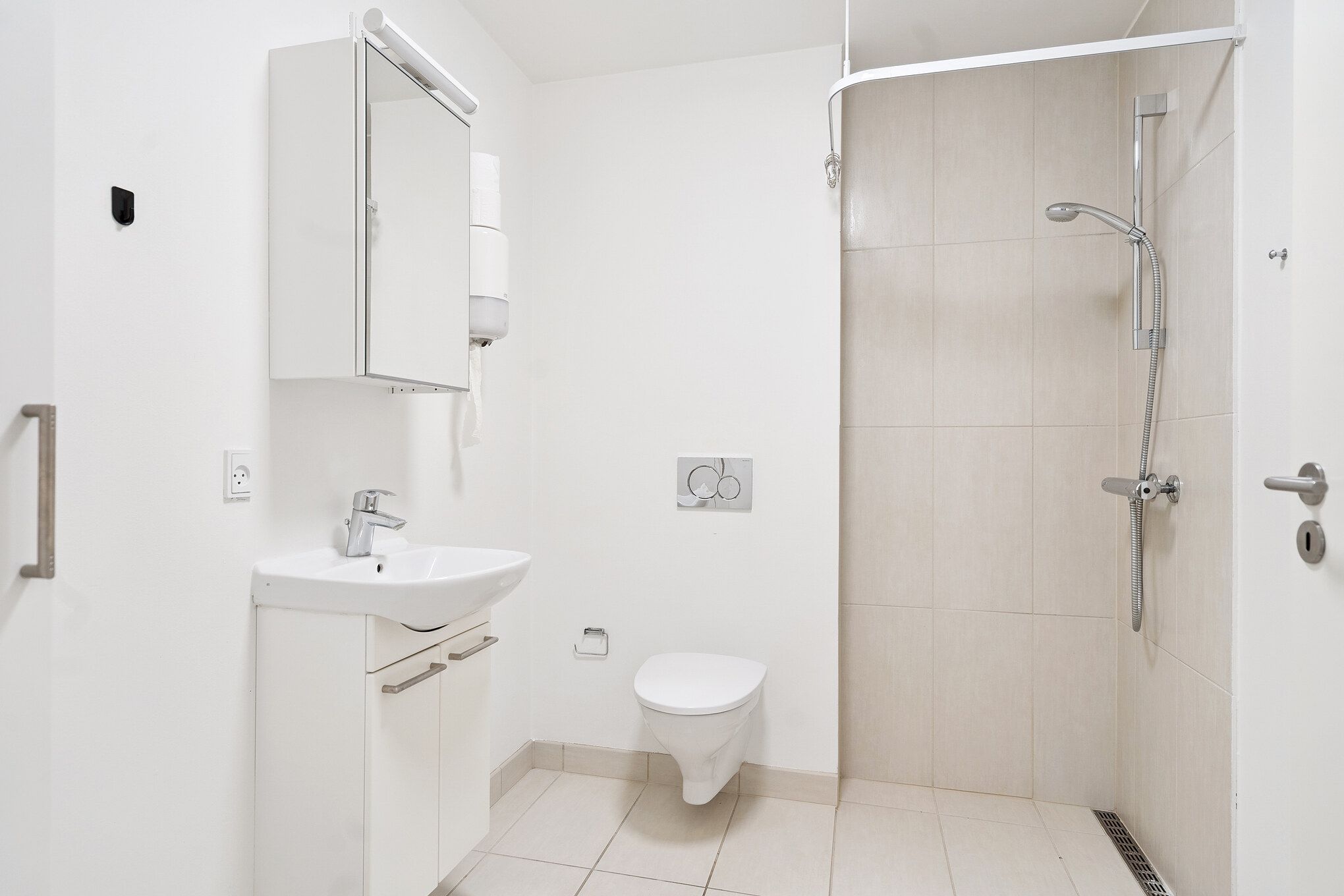 Et minimalistisk, hvidt badeværelse med høj kvalitet og funktionel design. Et moderne toilet med en hvid keramik og en håndvask med integreret håndklædeholder. En moderne brusekabine med en vandhane og en håndklædeholder.
