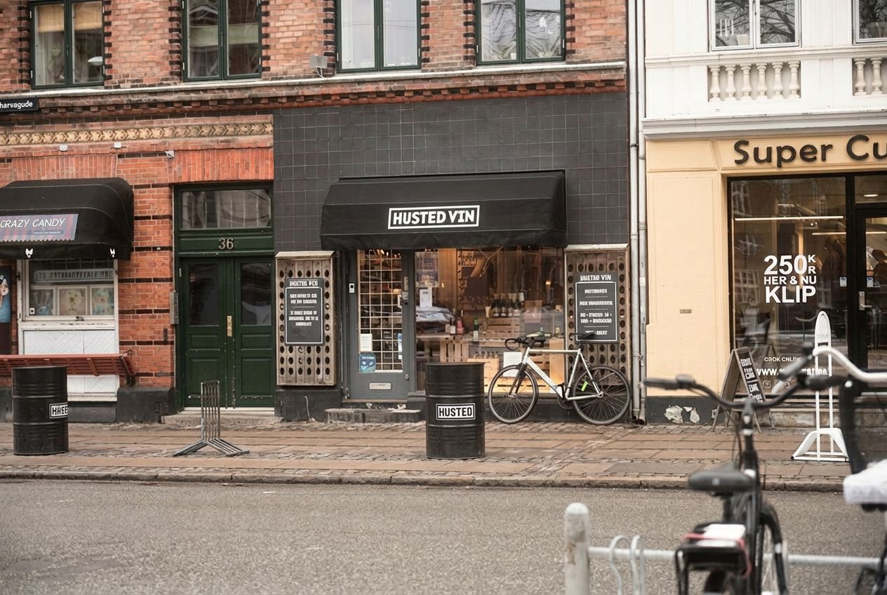 Butik med udsalg af vin og øl, samt to cykler parkeret udenfor. En af cyklerne har en flaske fastgjort til sædet.