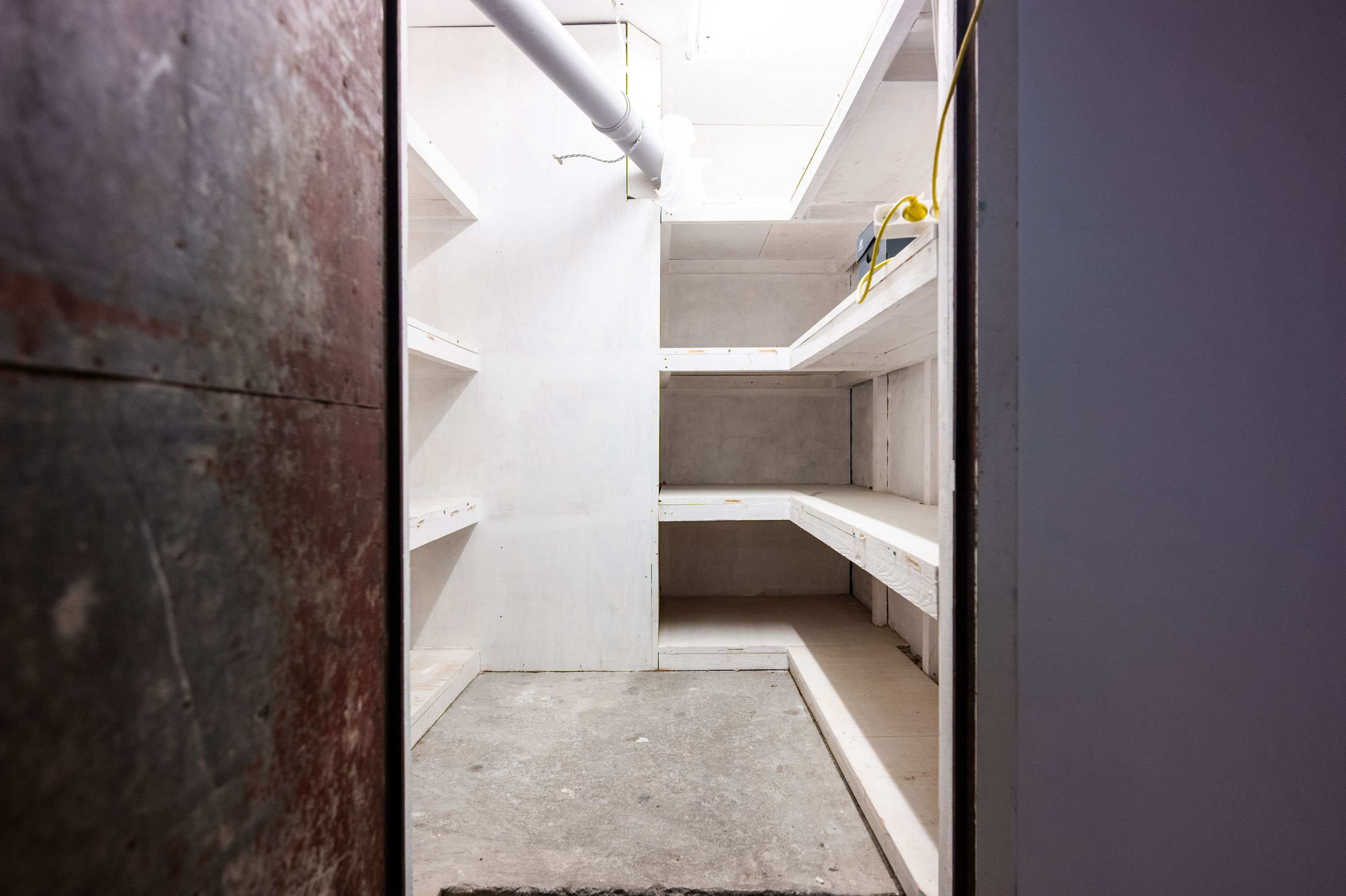 Ledig kælderrum med loftsbjælker og metalliske væggen og høje lofter til leje i København. Et kælderrum med lysegule vægge og højloftede rum