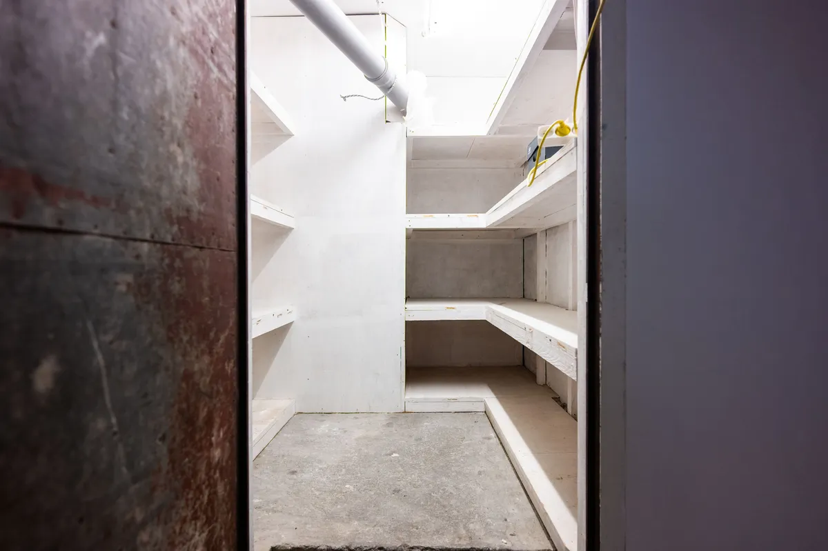 Ledig kælderrum med loftsbjælker og metalliske væggen og høje lofter til leje i København. Et kælderrum med lysegule vægge og højloftede rum