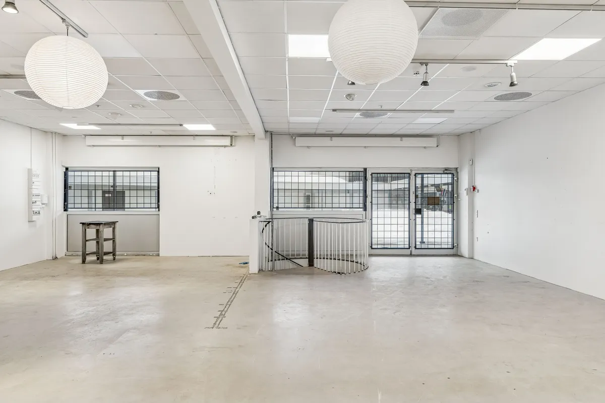 Store, hvide butikslokaler med glasruder og hvide vægge samt lysekroner og et højt loft med runde loftsventiler og et snoet trappeværk