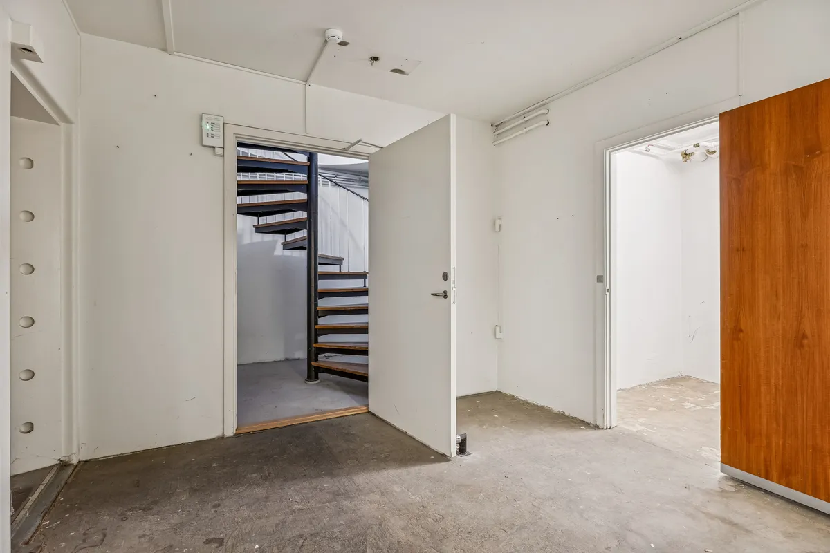 Tomt rum med åben dør til kælder og trappe. Dekorative hængebolte og et indbygget sikringsskab. Større rum med åbne døre til venstre og højre