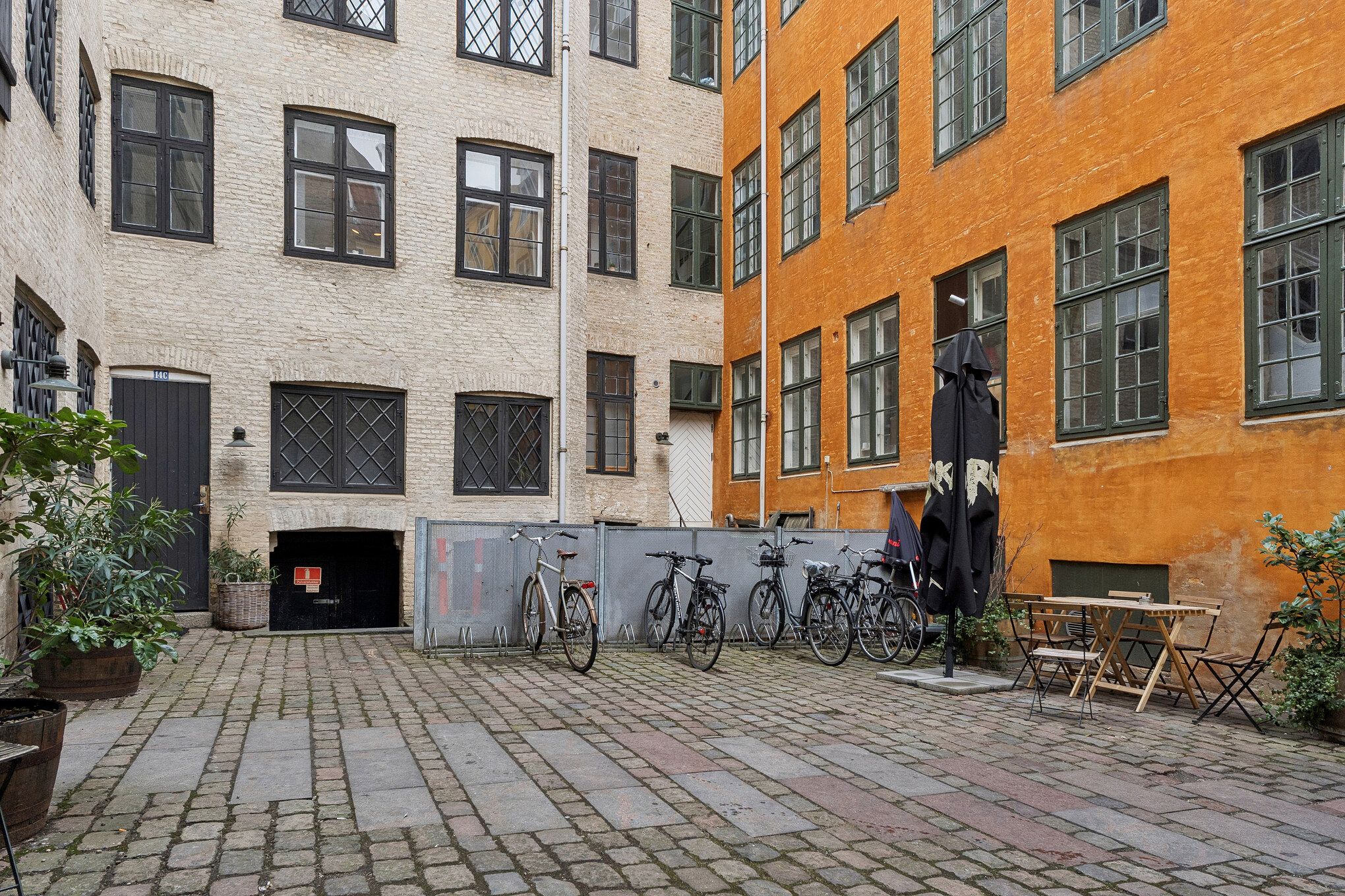 Et kontorlejemål i baghuset på Kompagnistræde med flere cykler og plantager og en terrasse med sæde og bord.
