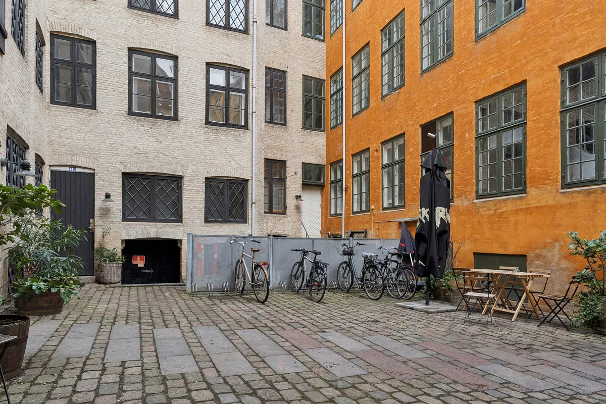 Et kontorlejemål i baghuset på Kompagnistræde med flere cykler og plantager og en terrasse med sæde og bord.
